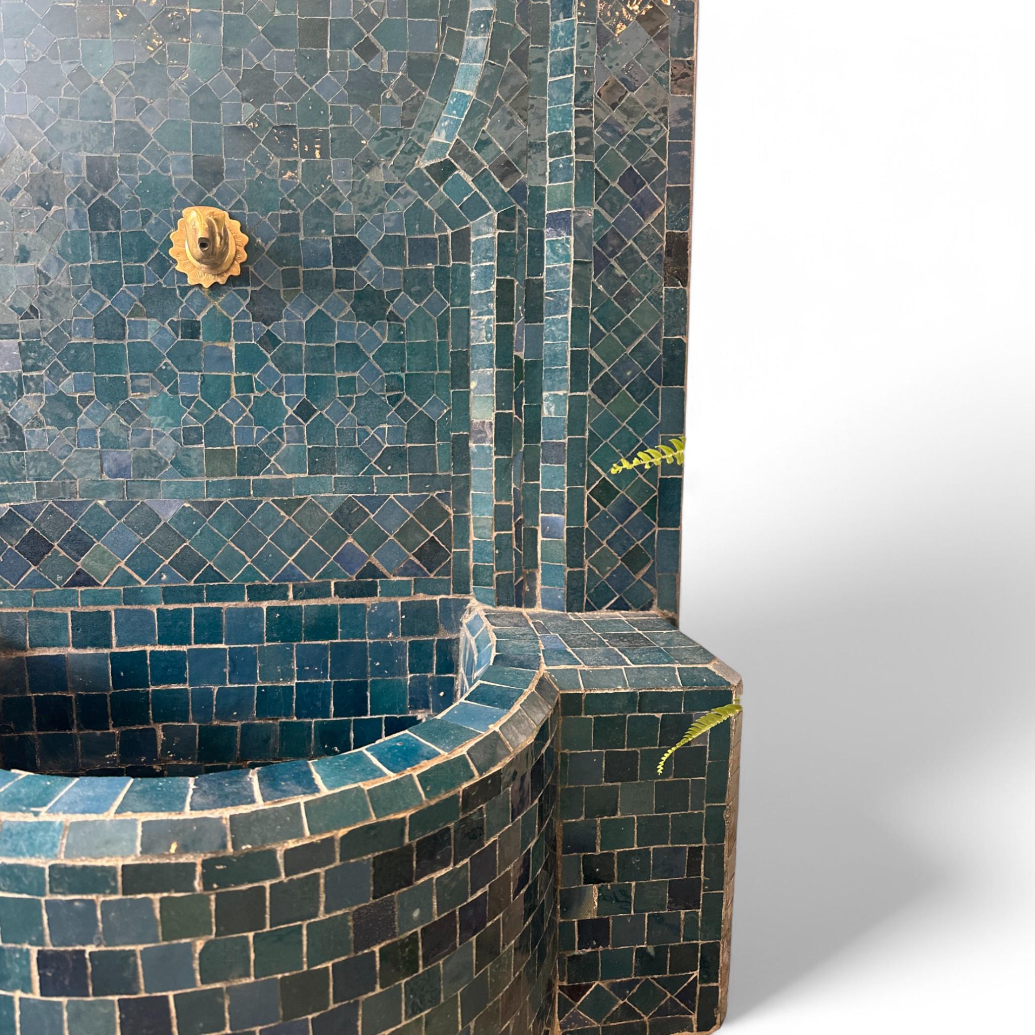 Dale un toque de Marrakech a tu casa o jardín con esta fuente de agua de mosaico marroquí hecha a mano. Con intrincados motivos geométricos en ricos tonos azules y un caño de latón, es una impresionante mezcla de arte y funcionalidad que añade