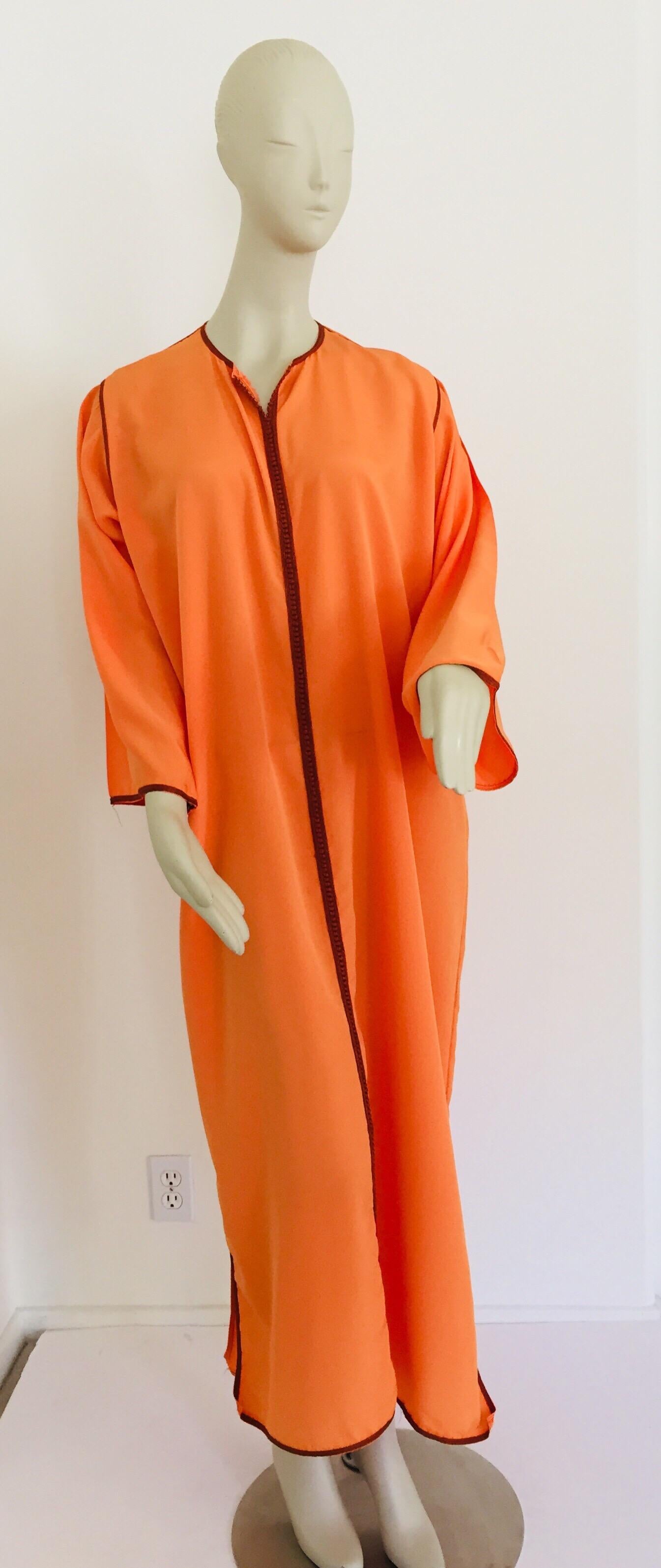 Elegant Moroccan caftan orange color with embroidered trim,
circa 1970s.
Caftan Gown, Tangerine
Round contrast neckline; button-loop placket.
Long bell sleeves.
Relaxed silhouette.
Straight skirt and hem.
This long maxi dress kaftan trim is