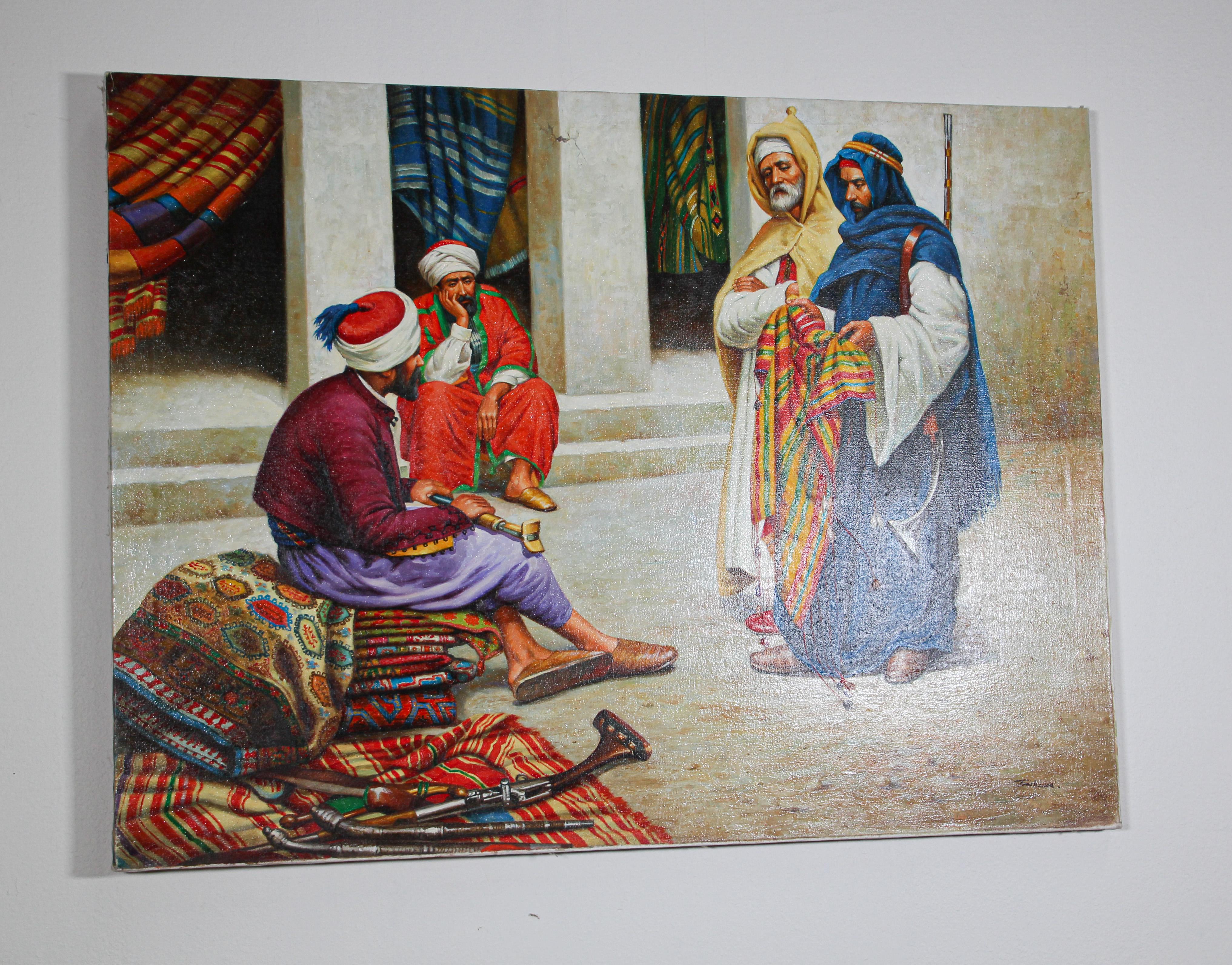 Moroccan orientalist oil on canvas painting of a 19th century Moroccan rug market scene with an sellers seating on a pile of carpet and two other men wearing traditional colorful robes standing and checking the goods.
The background depict an old