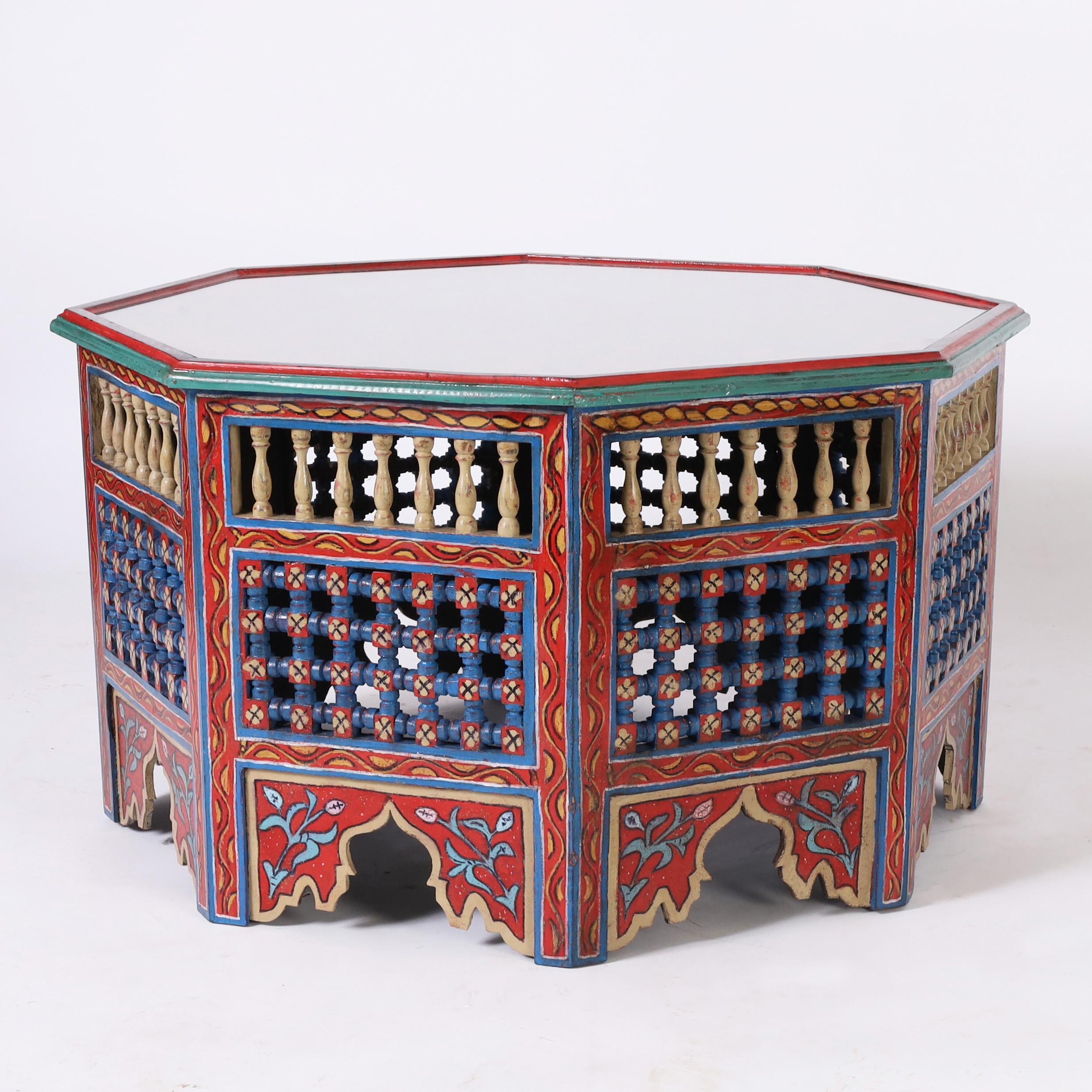 Remarquable table marocaine ancienne en bois dur indigène de forme octogonale décorée à la main de motifs floraux symboliques aux couleurs chaudes caractéristiques de la Méditerranée. La base présente des balustrades tournées, des frettes ouvertes
