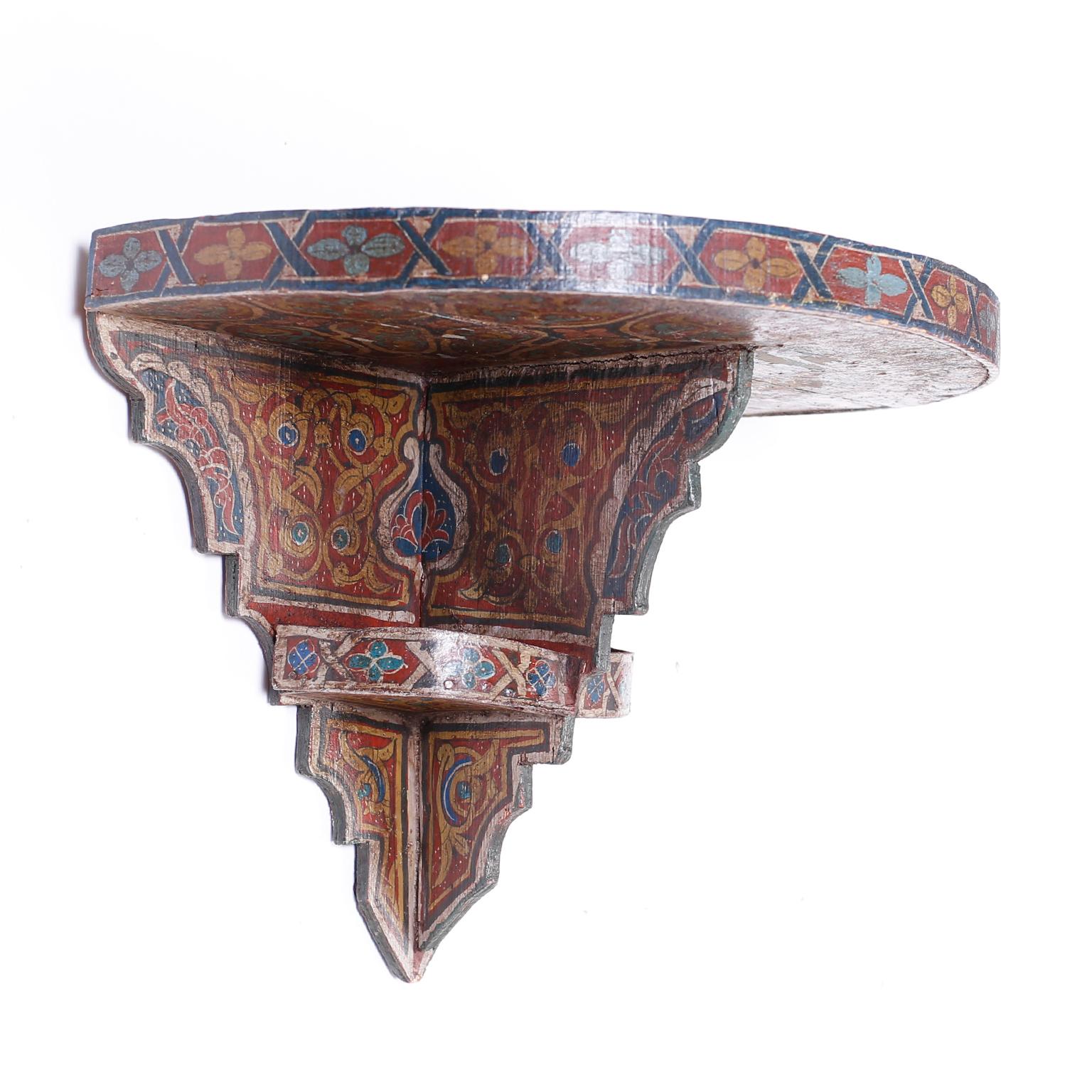 Antique Moroccan wall shelf crafted in wood with a demi lune form top shelf and painted with distinctive rustic mediterranean colors.