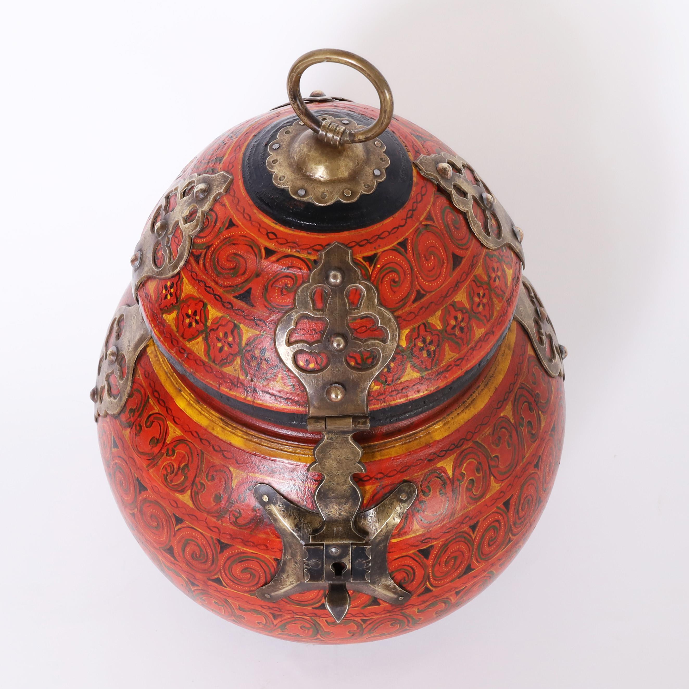 Striking gourd form vintage Moroccan lidded box or vessel hand crafted in indigenous wood and painted with floral designs in distinctive mediterranean colors highlighted with decorative brass hardware. 