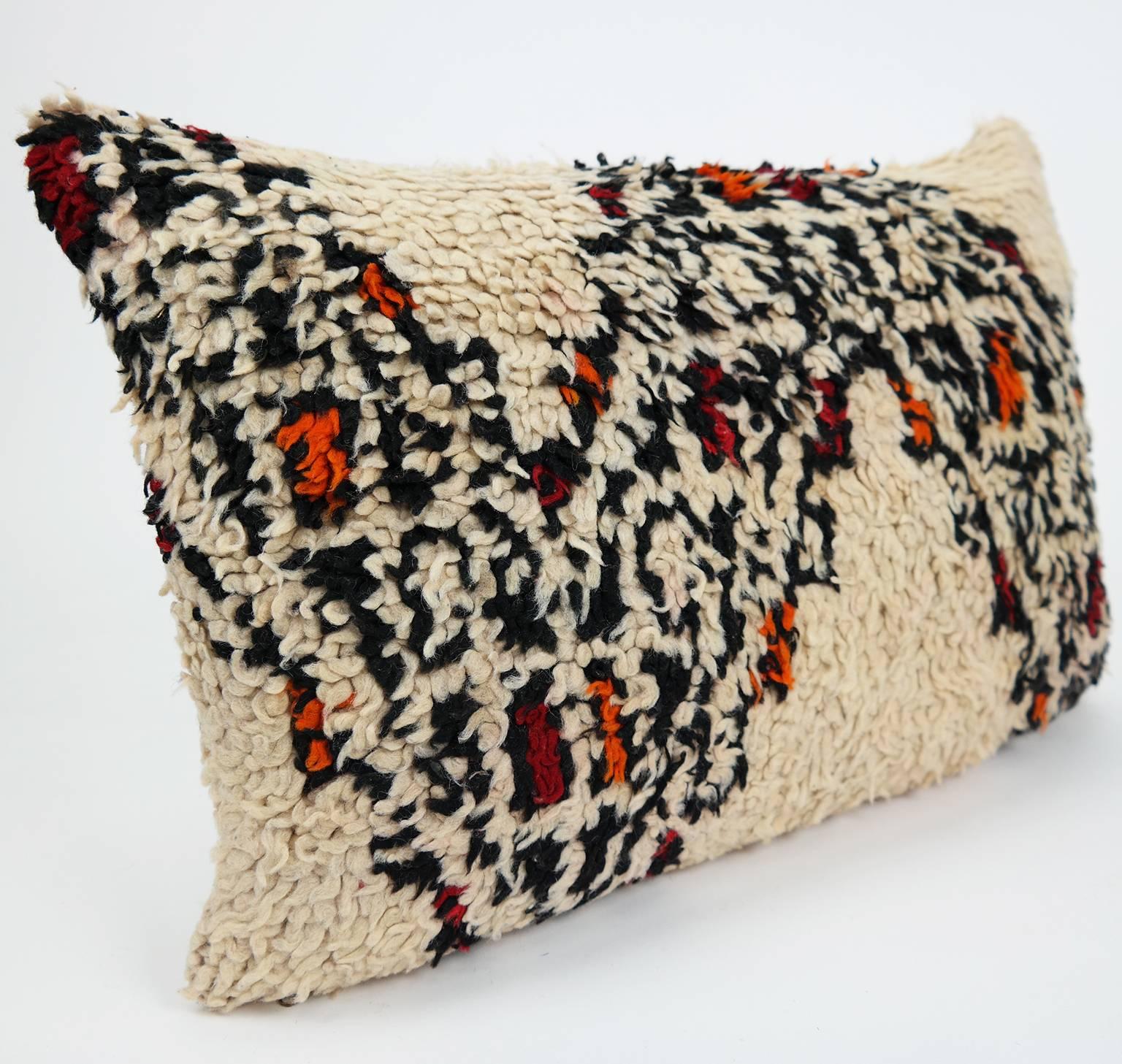 Beautiful cushion with warm red and orange color accents, custom made from a vintage Beni Ourain rug made in Morocco. Our Beni cushions are a one-of-a-kind, no two are ever the same. Beni Ourain rugs have a story to tell. The woolly Berber rugs have
