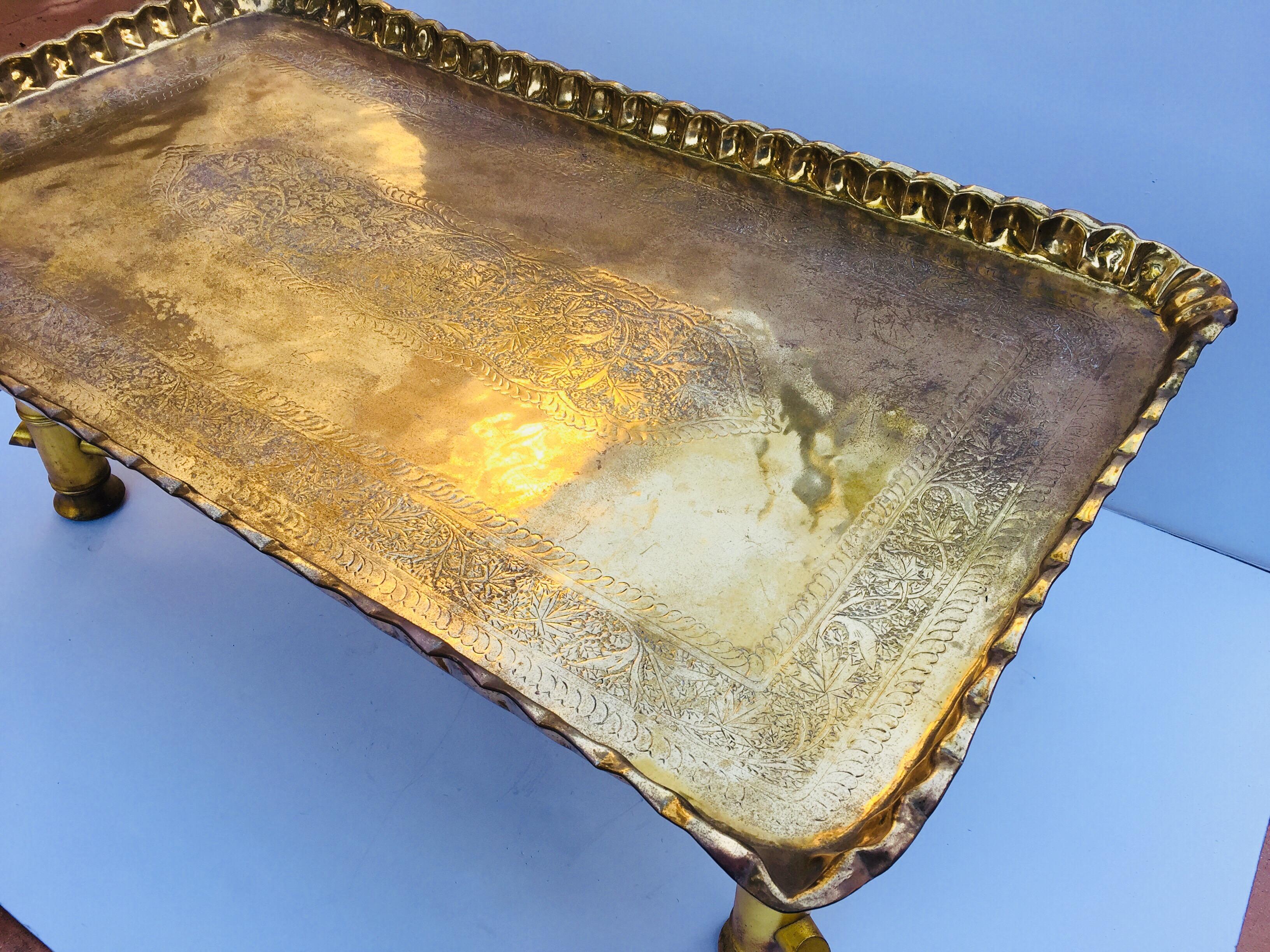 Moroccan rectangular brass tray coffee table.
Large rectangular hand etched, hammered and embossed, chiseled brass tray table on gilded wooden base in faux bamboo design. 
Middle Eastern Moroccan style coffee or cocktail table great to use indoor or
