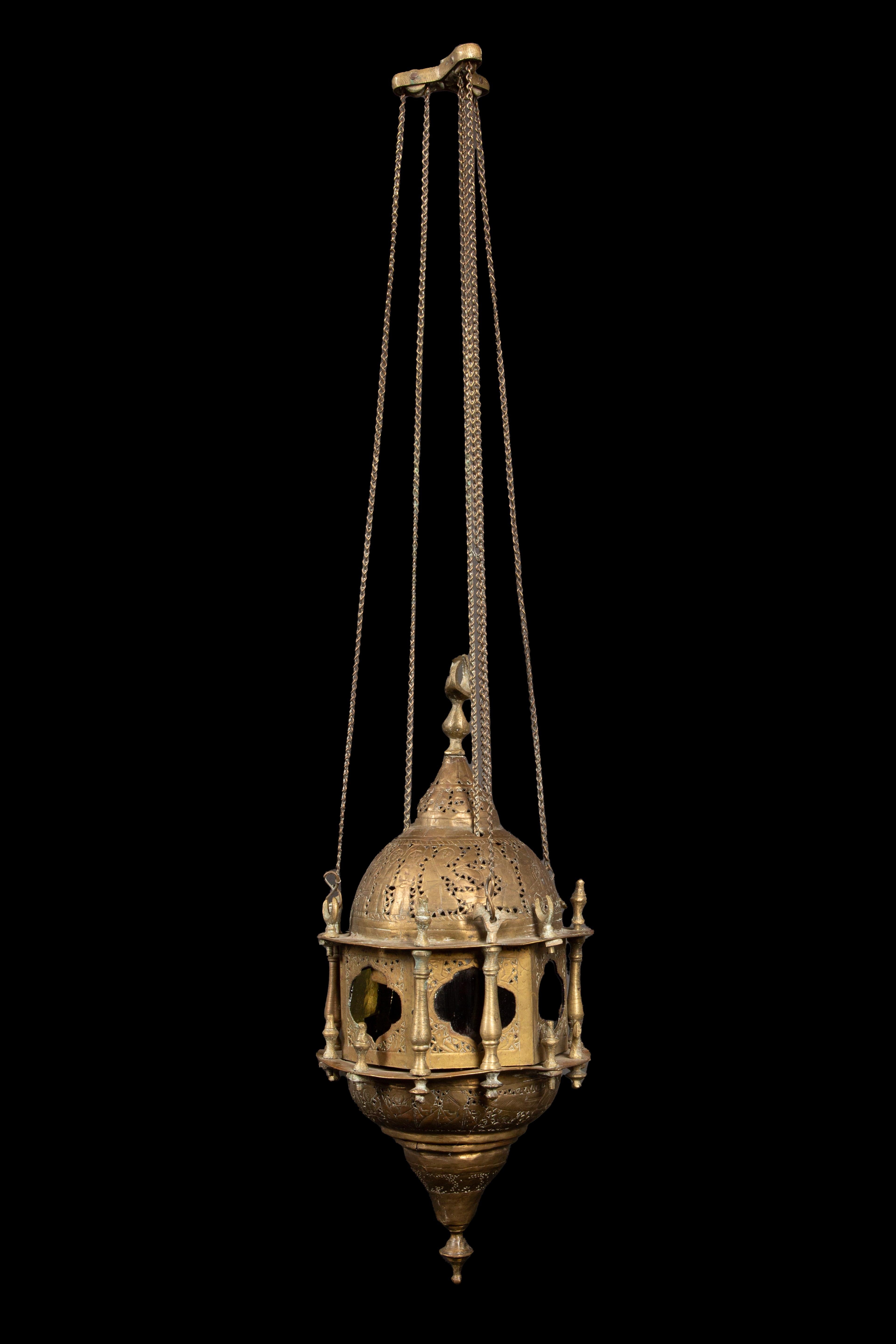 Moroccan reticulated brass lantern, small, and of typical form with pierced domed top suspended from a canopy by chains, and with multicolored glass-paned sides separated by colonnettes. 31
