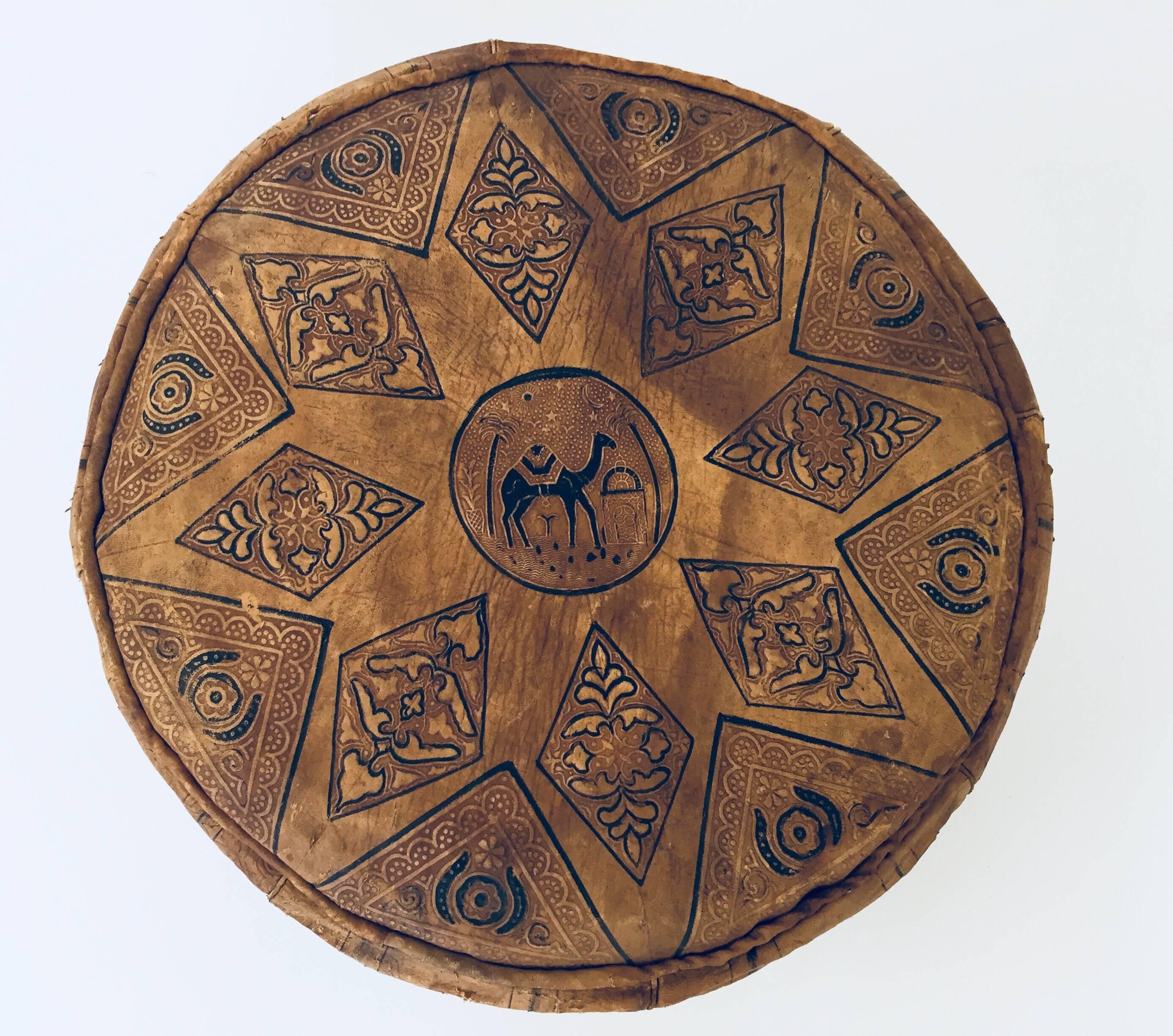 Moroccan brown round pouf hand tooled and embossed in Fez Morocco. 
Beautiful geometrical designs are hand-stitched and hand stamped on this Moroccan stool by expert Artisan. 
Distressed leather, damaged on one side.
Size is 18.5 in diameter x 9.5