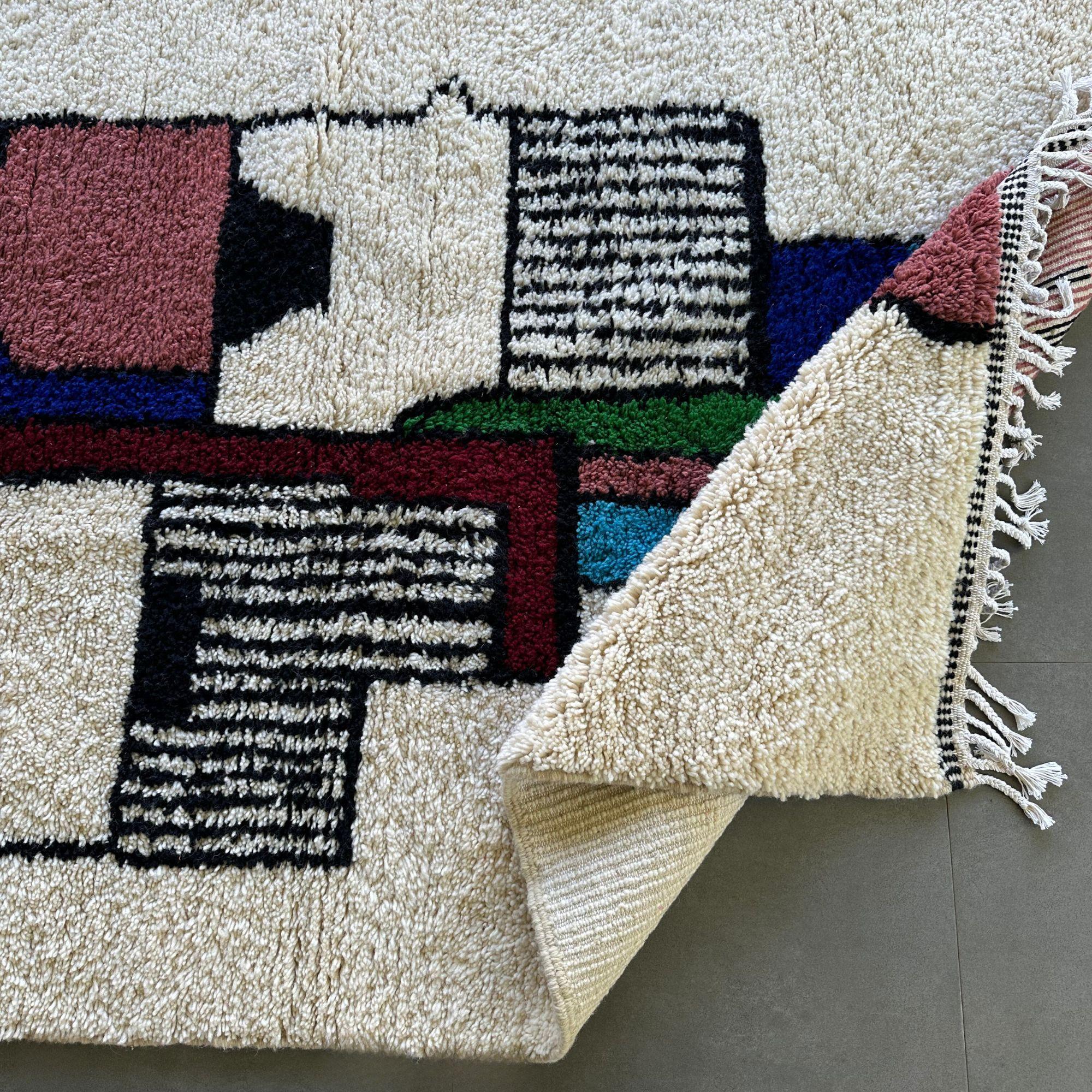 Introducing the Artisan Signature, a delightful Moroccan rug perfect for adding a touch of whimsy and color to a kids' room. This charming rug features a pristine white background adorned with a playful tribal Berber face design in vibrant shades of