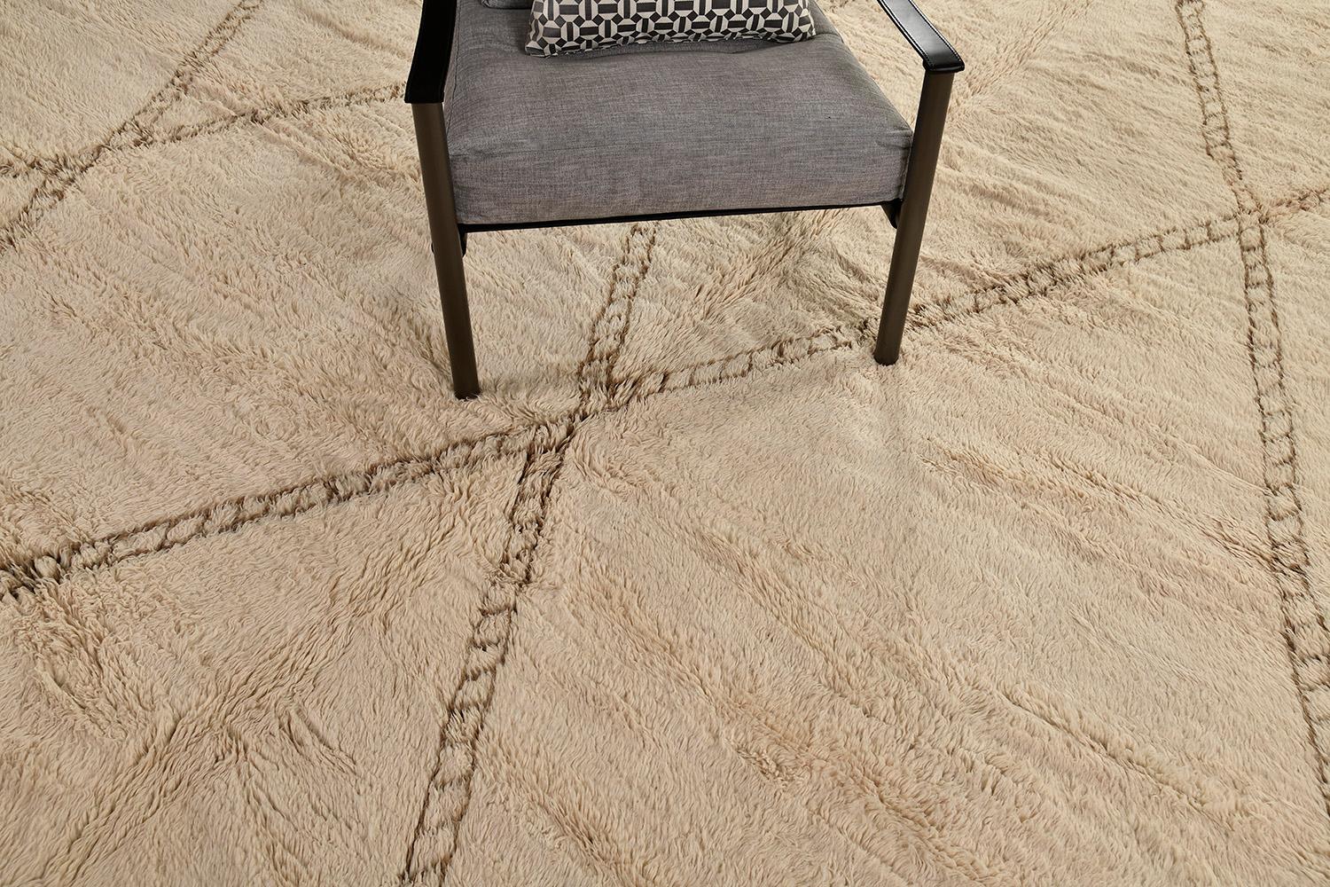 Déjate cautivar por esta lujosa alfombra de Marruecos. Tiene un dibujo de rombos a través de la alfombra marrón claro natural y muestra el diseño en contraste perfilado que la hace más única. Hunde los pies en una alfombra de la tribu del Medio