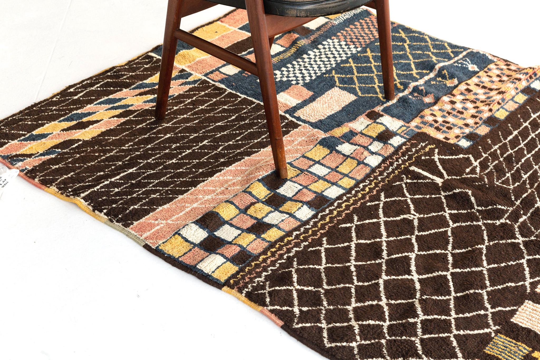 A masterful Moroccan rug in the Atlas Collection overlaid with variegated geometric patterns composed of an array of symbolic Berber motifs. The abrashed chocolate brown field highlights a myriad of ambiguous organic shapes in the most sought after