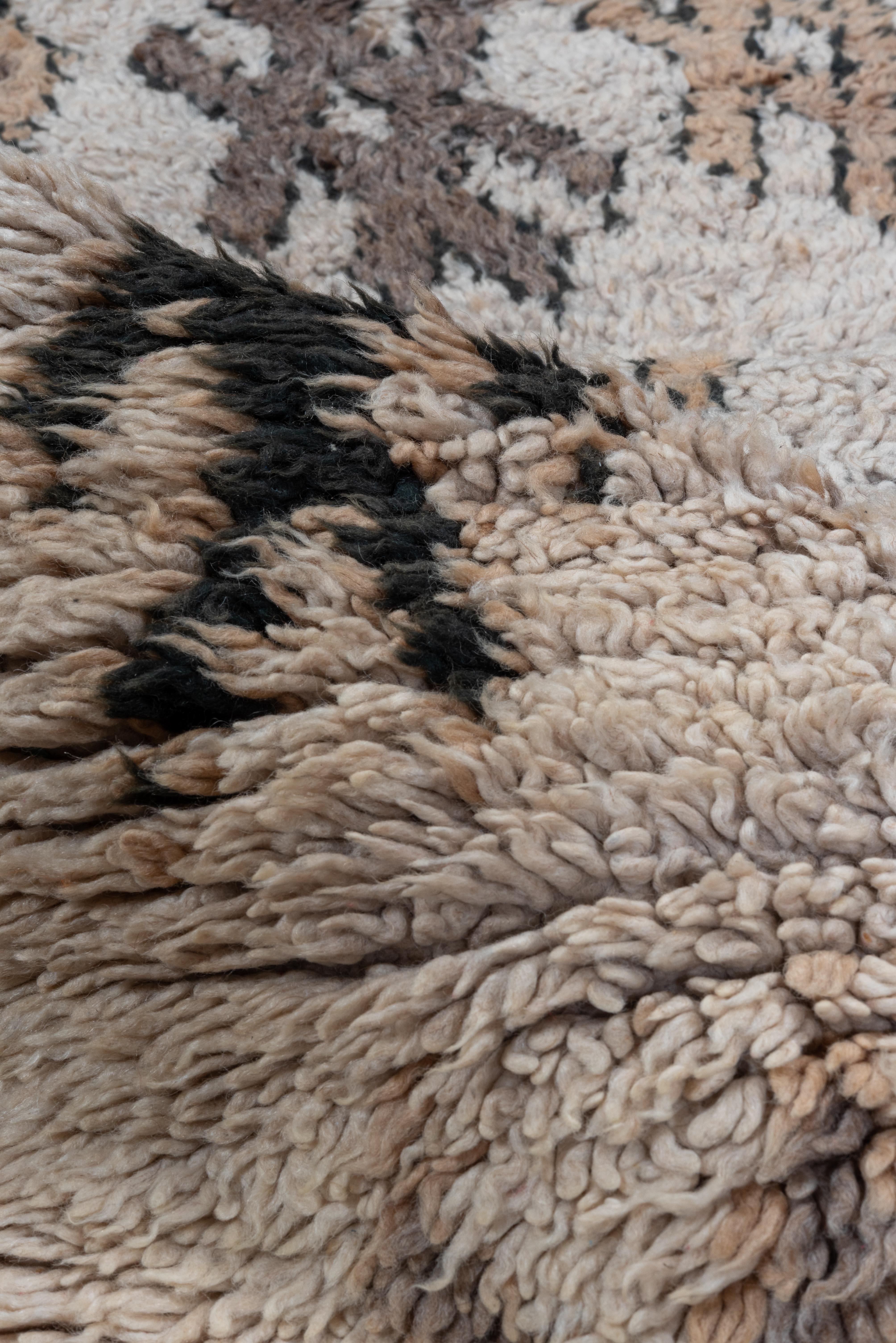Geometrische Muster bedecken diesen Teppich in seinem Feld mit schneeflockenähnlichen Formen, auf einem cremeweißen Wollgrund - dieser handgeknüpfte Marokkaner zeigt Gebrauchs- und Liebesspuren. 