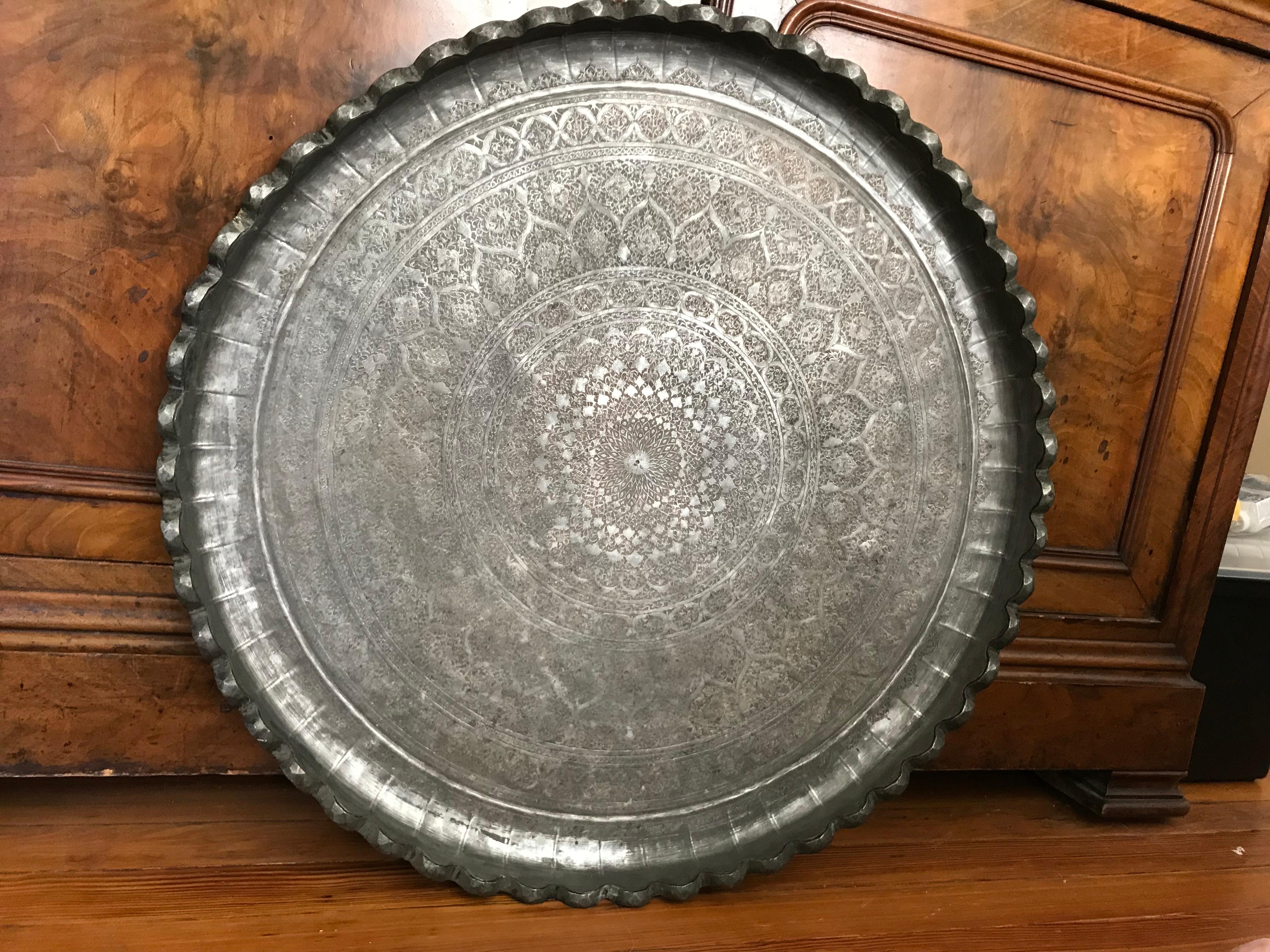 A large-scale 19th century charger with intricate incised Moorish inspired decoration throughout. With deeply scalloped hand-hammered edge , floral arabesques spiralling from the centre, birds in cartouches in an outer ring. Similar to the