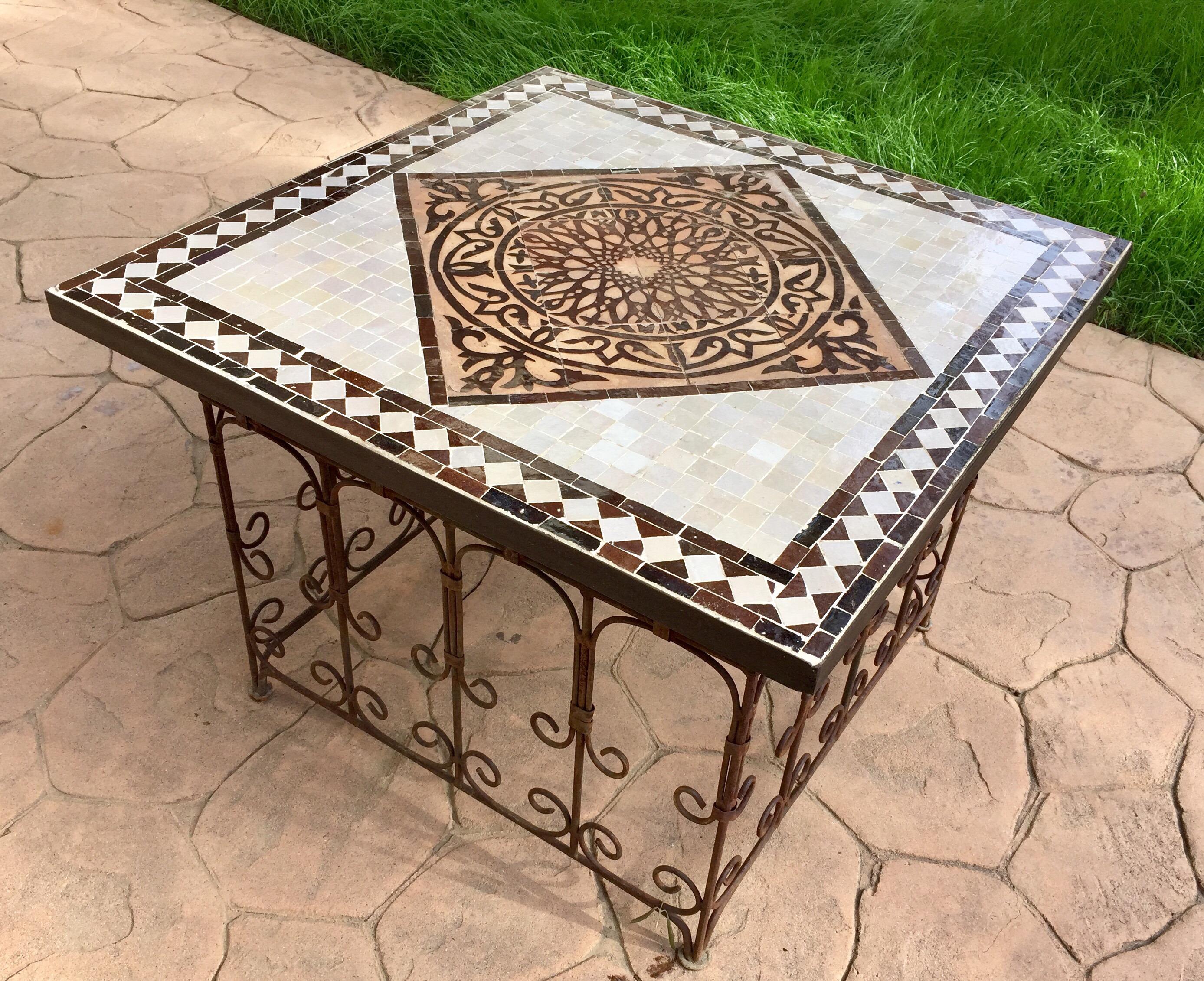 Great Moroccan mosaic tile coffee table, or side table delicately handcrafted in Fez with traditional Moorish geometric hand chased design in earth tone brown, back, off white colors glazed tiles.
The handcrafted zellige tile table sits on an iron