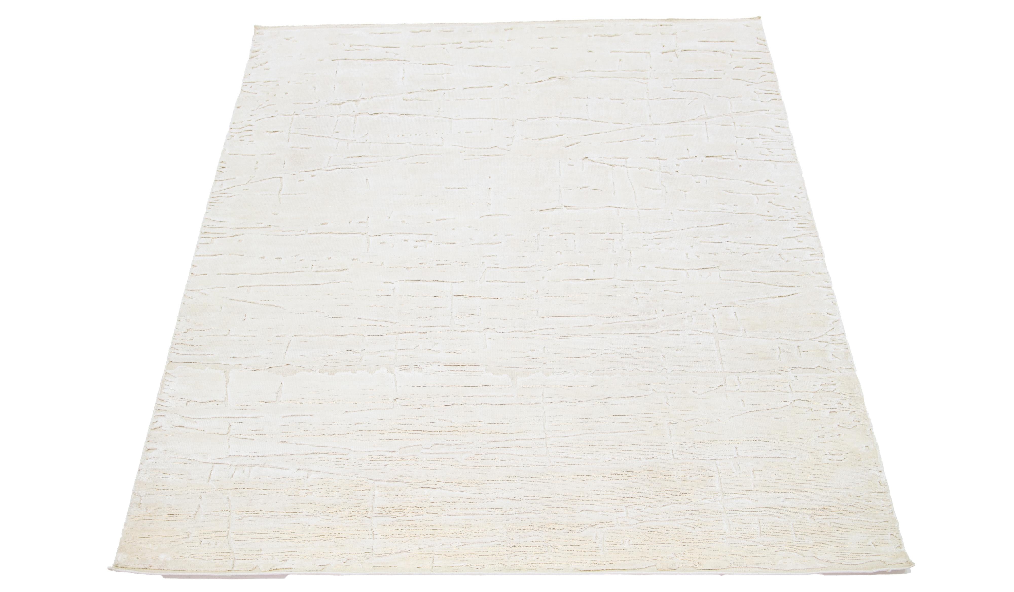 This wool rug, expertly hand-knotted, features a contemporary Moroccan design in subdued beige tones contrasted against a striking ivory backdrop, resulting in a strikingly minimalist presentation.

This rug measures 8' x 10'2