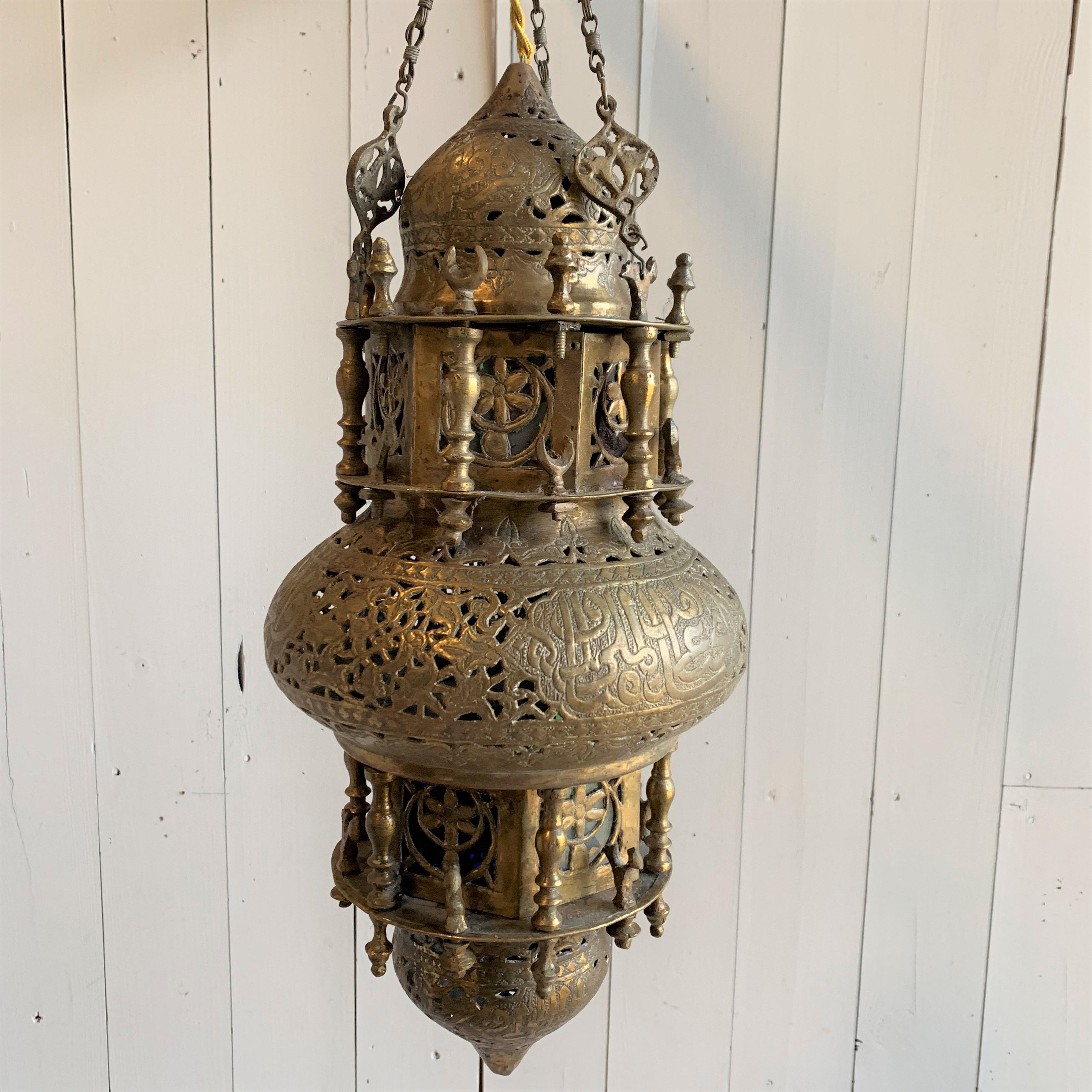 A Moroccan style hanging lantern in pierced and embossed brass with colored glass panes. Recently rewired.