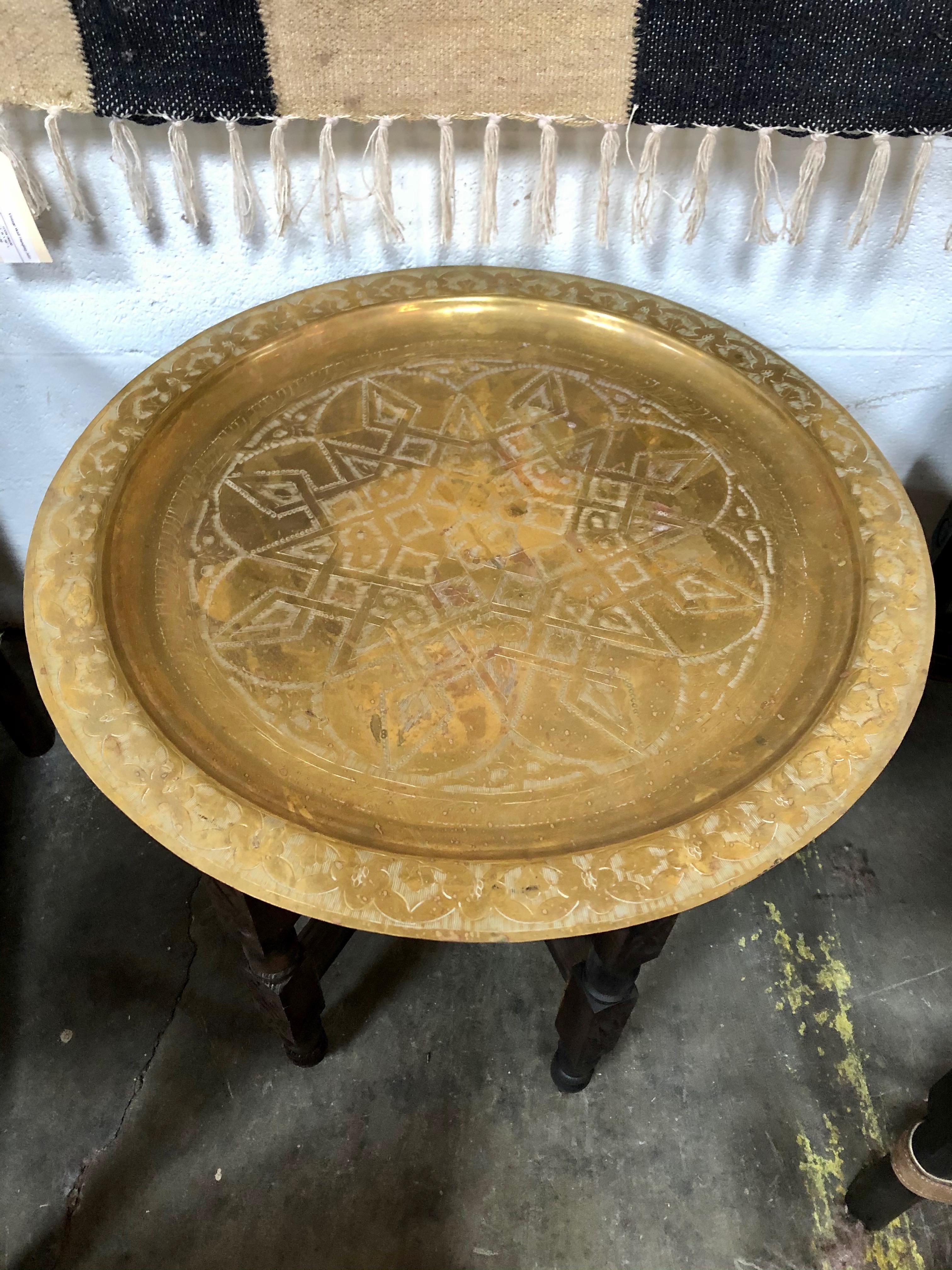 This Moroccan tray table is made with brass and features beautiful etchings into its top surface. The brass tray sits on six wooden legs also hand carved. It measures at 24