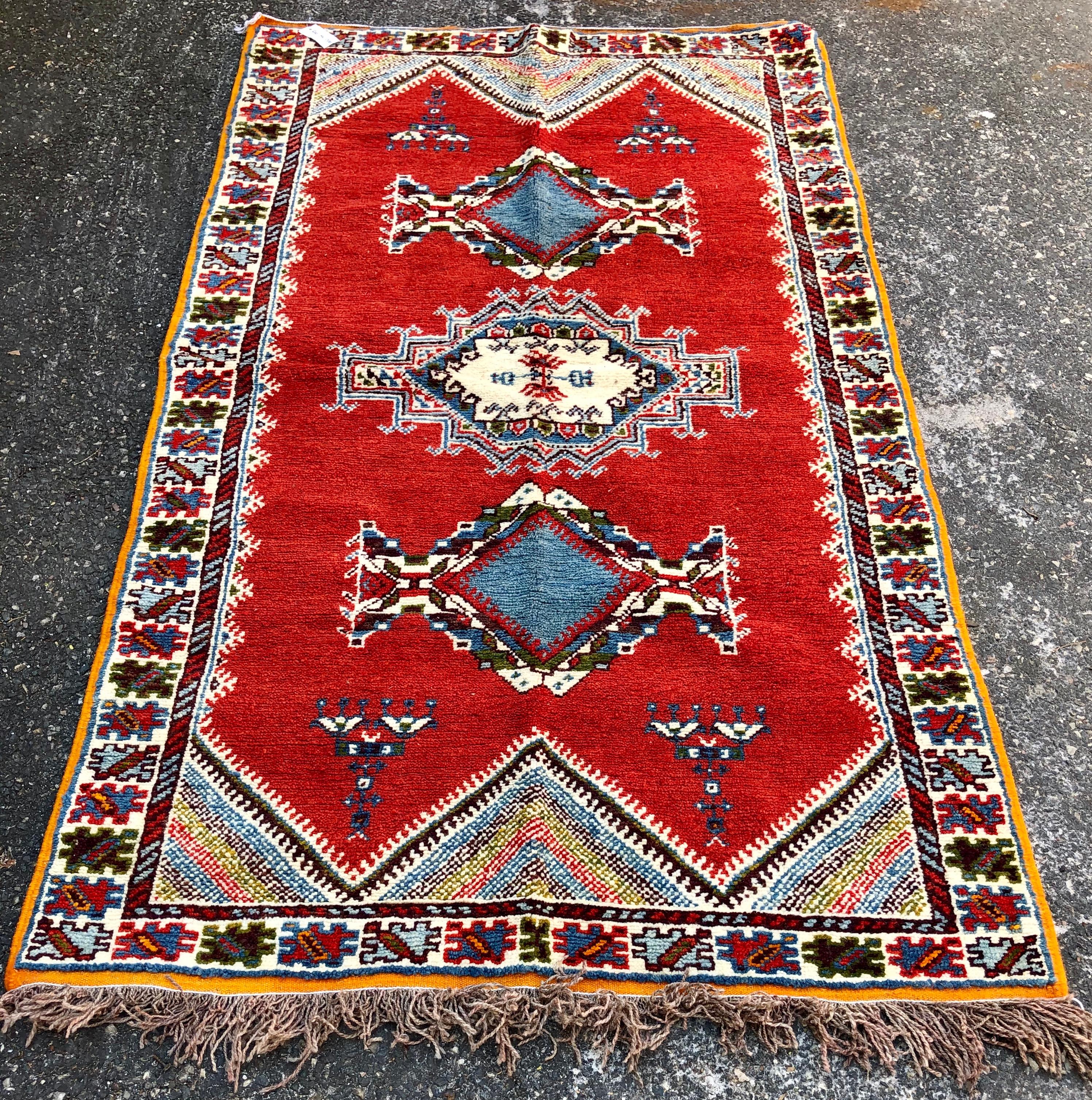 A one of a kind Moroccan tribal handwoven wool rug. The rug is finely crafted of locally sourced high quality wool and organic vegetables dyes. The handwoven rug features intricate geometrical motifs in the shape of large diamonds in blue and a