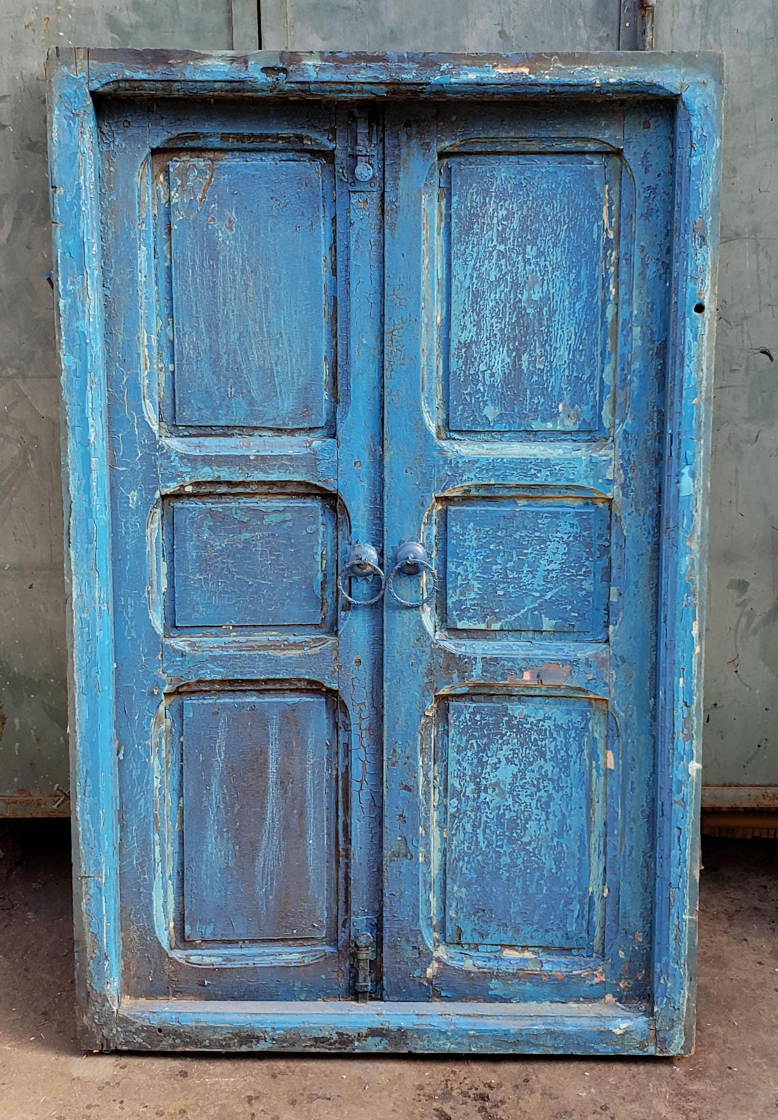 Aged turquoise handmade Moroccan cedar wooden window frame measuring approximately 49” in height, 31.5” in width, and 7” in depth. Very old but has an amazing look. Old metal locks hold doors closed at all times if necessary. This would be an