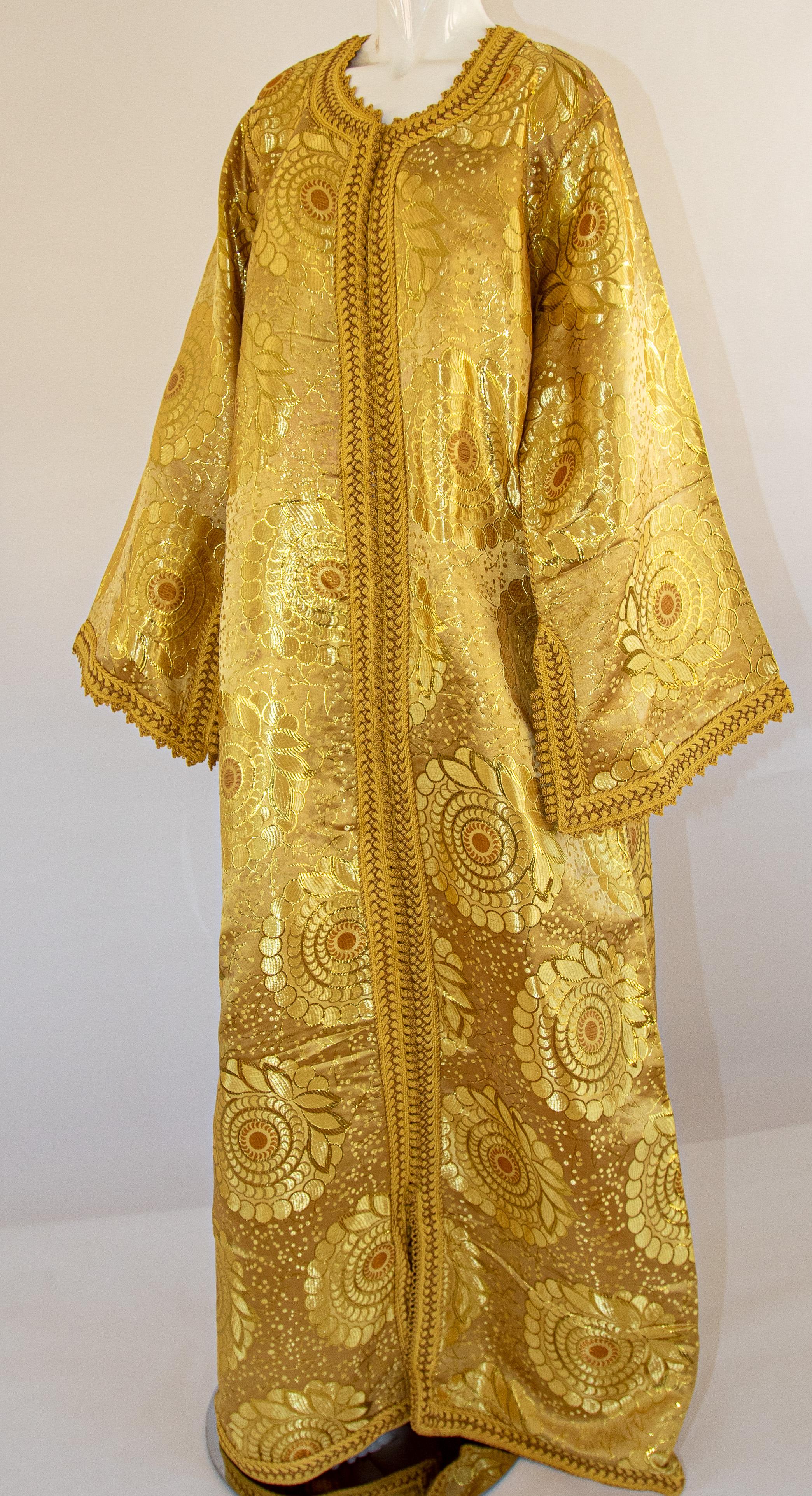 Robe caftan marocaine vintage exotique en brocart métallique doré, circa 1970.
Le luxueux caftan mauresque est conçu avec un brocart métallique or brillant.
Le devant de l'élégante robe caftan est orné de boutons dorés tissés et de boucles qui