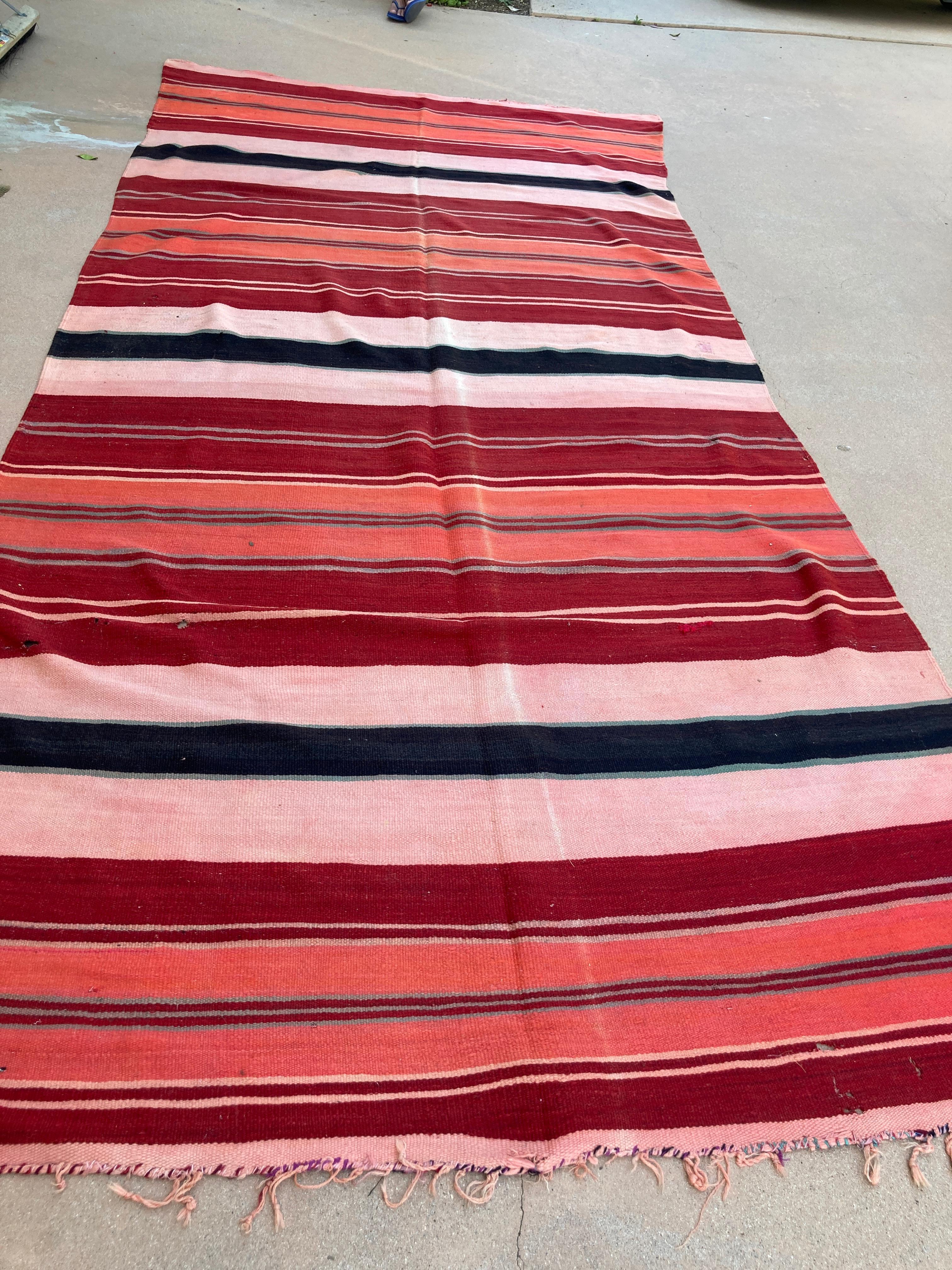 Vintage Moroccan flat-weave Kilim rug.
Large size vintage Moroccan rug, handwoven by Berber women in Morocco for their own use.
This rug was made using flat-weave technique with linear pattern of alternating stripes in different colors in rust