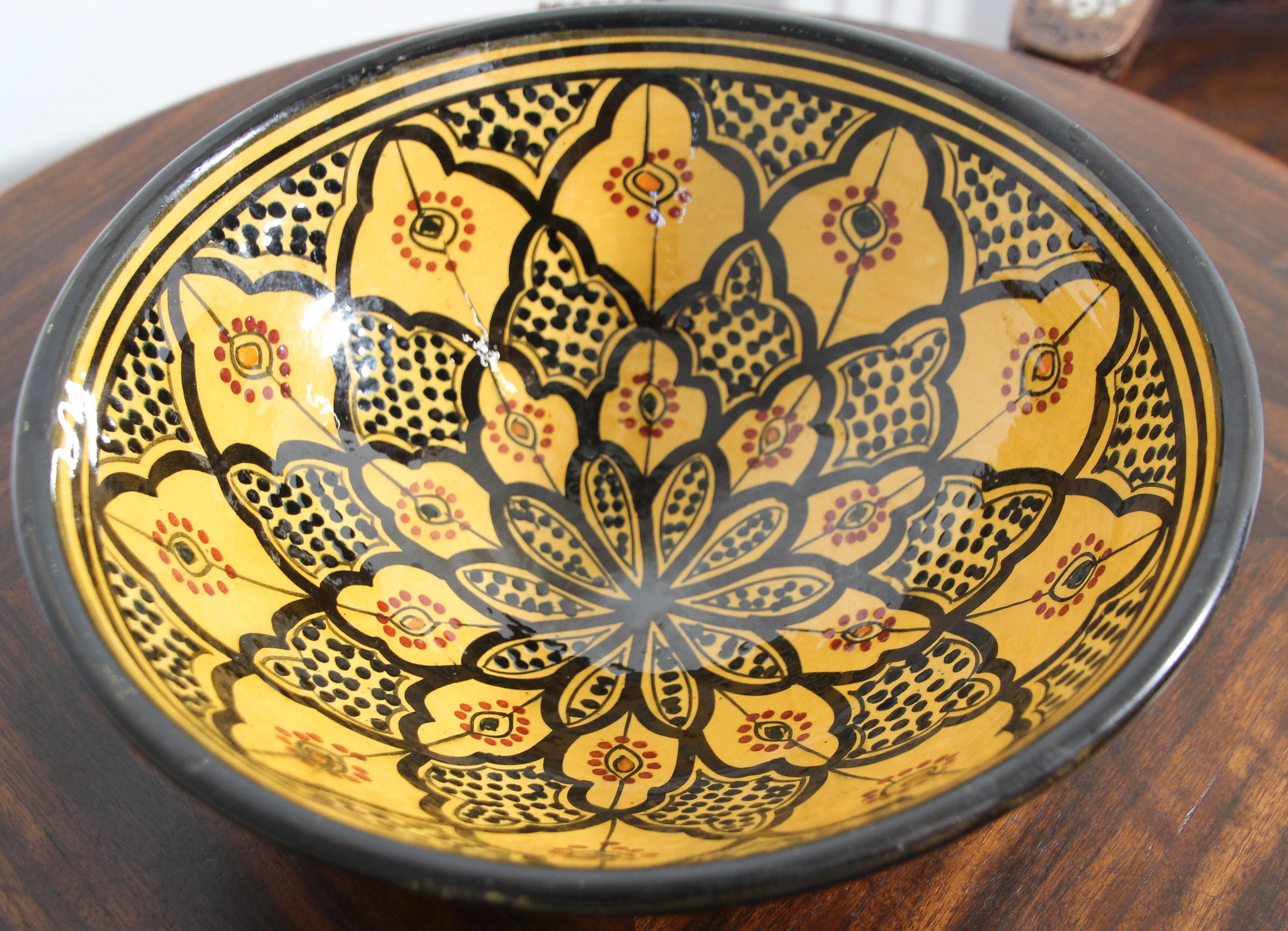 Bol décoratif marocain en céramique émaillée, peint à la main, avec un fond jaune et orné de motifs géométriques noirs mauresques.
Signé au dos en arabe 