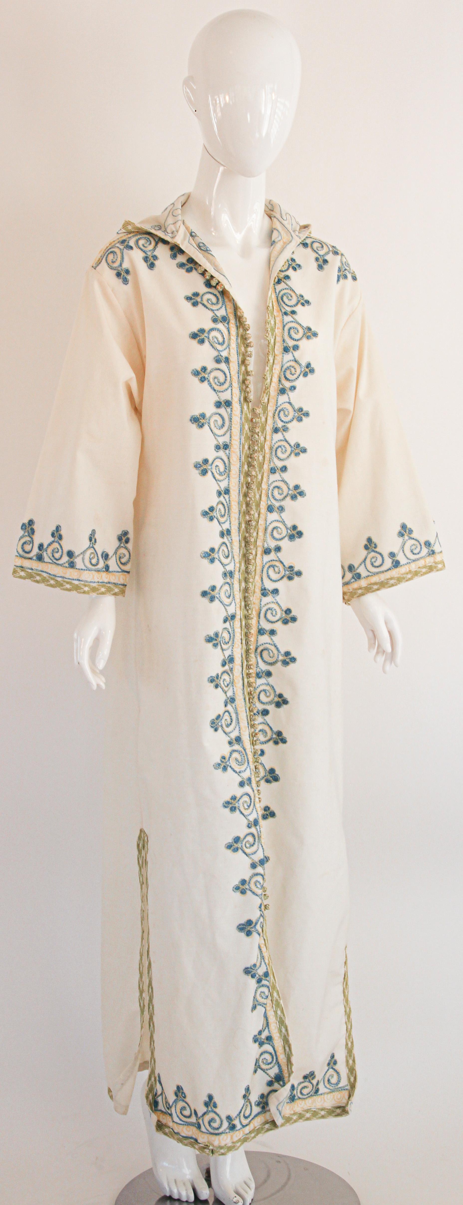 Eleganter marokkanischer Kaftan aus weißer Baumwolle im Vintage-Stil mit türkisfarbener und goldener Stickerei,
ca. 1970er Jahre.
Dieser Kaftan im langen Maxikleid ist vollständig von Hand bestickt und verziert.
Es wurde in Marokko gefertigt und hat