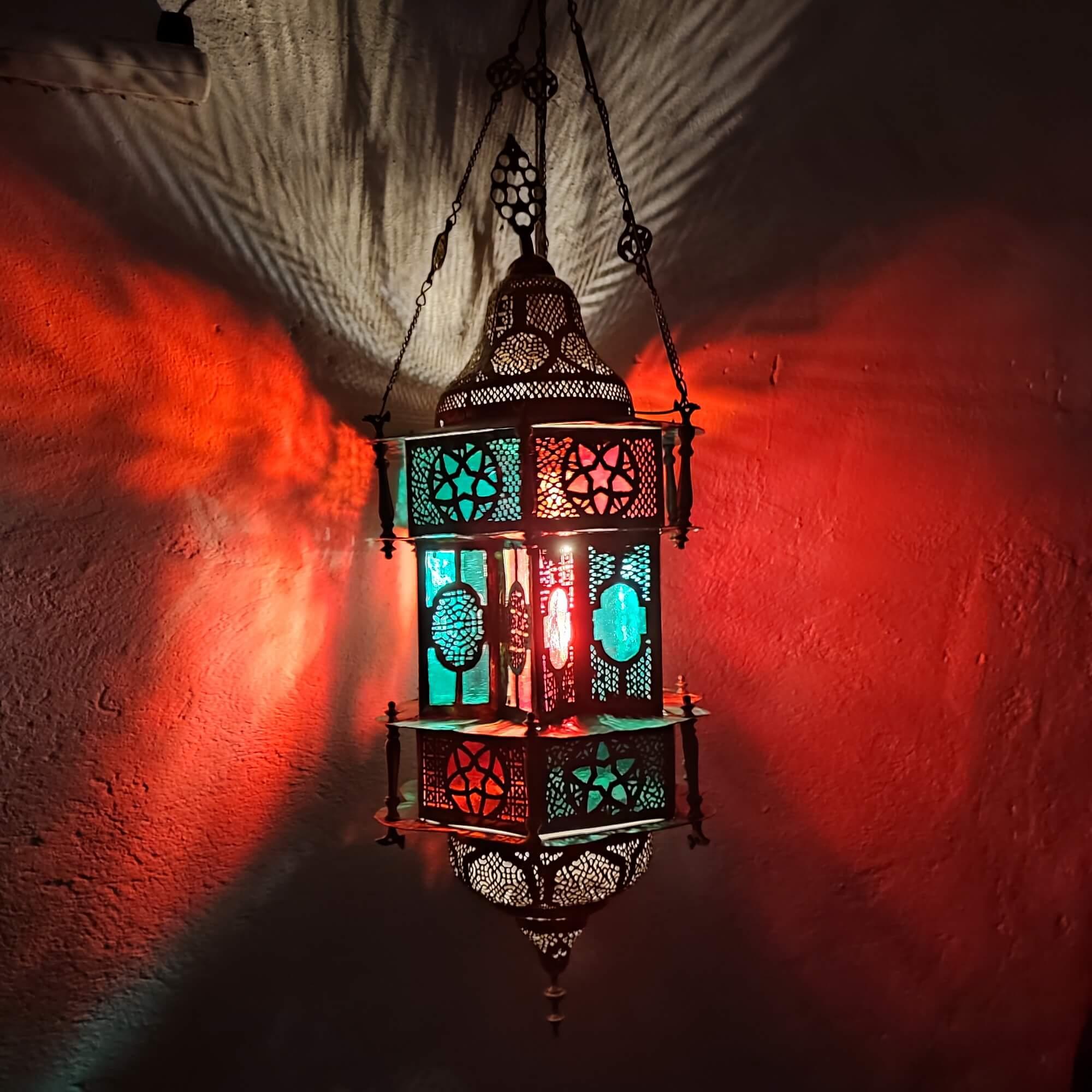 Vintage Moroccan pendant light. 
Newly rewired, and in very good condition with age appropriate patina. Original chains. Uses one single standard bulb E26/E27. Made of metal with cut-outs. Colored - red and teal green - glass inserts.