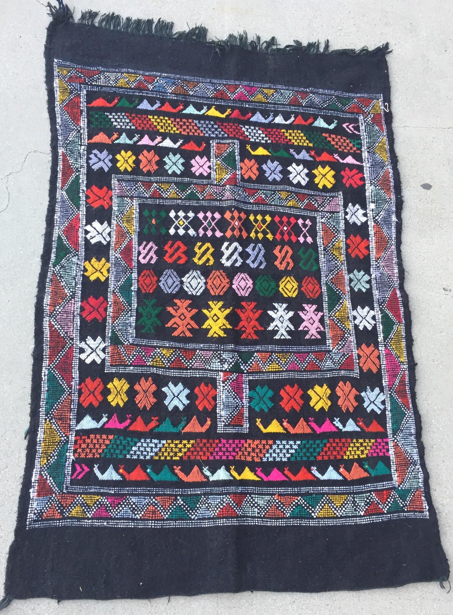 Moroccan vintage black tribal kilim rug, handwoven by Berber women in Morocco.Great mix of organic wo and cotton in black cor with flat-weaves.This kind of rug is typical of the Glaoui tribes of Morocco.Naif design of kamels and geometric