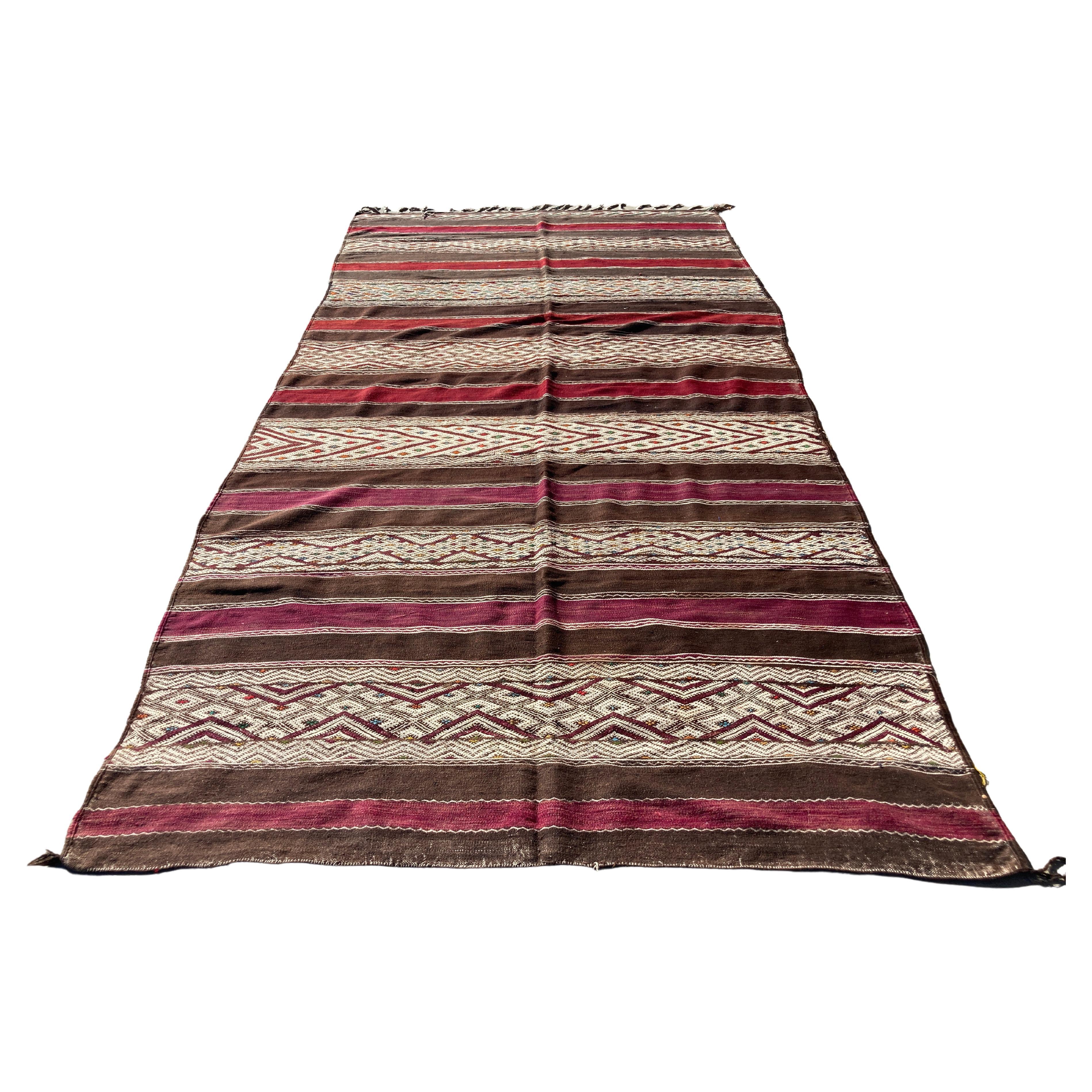 Moroccan authentic vintage flat-woven Tribal Kilim rug from the Middle Atlas of Morocco, North Africa. Handwoven clectible Moroccan textile in stripes of red and dark green, black and white geometrical Tribal African designs. Each carpet is a unique