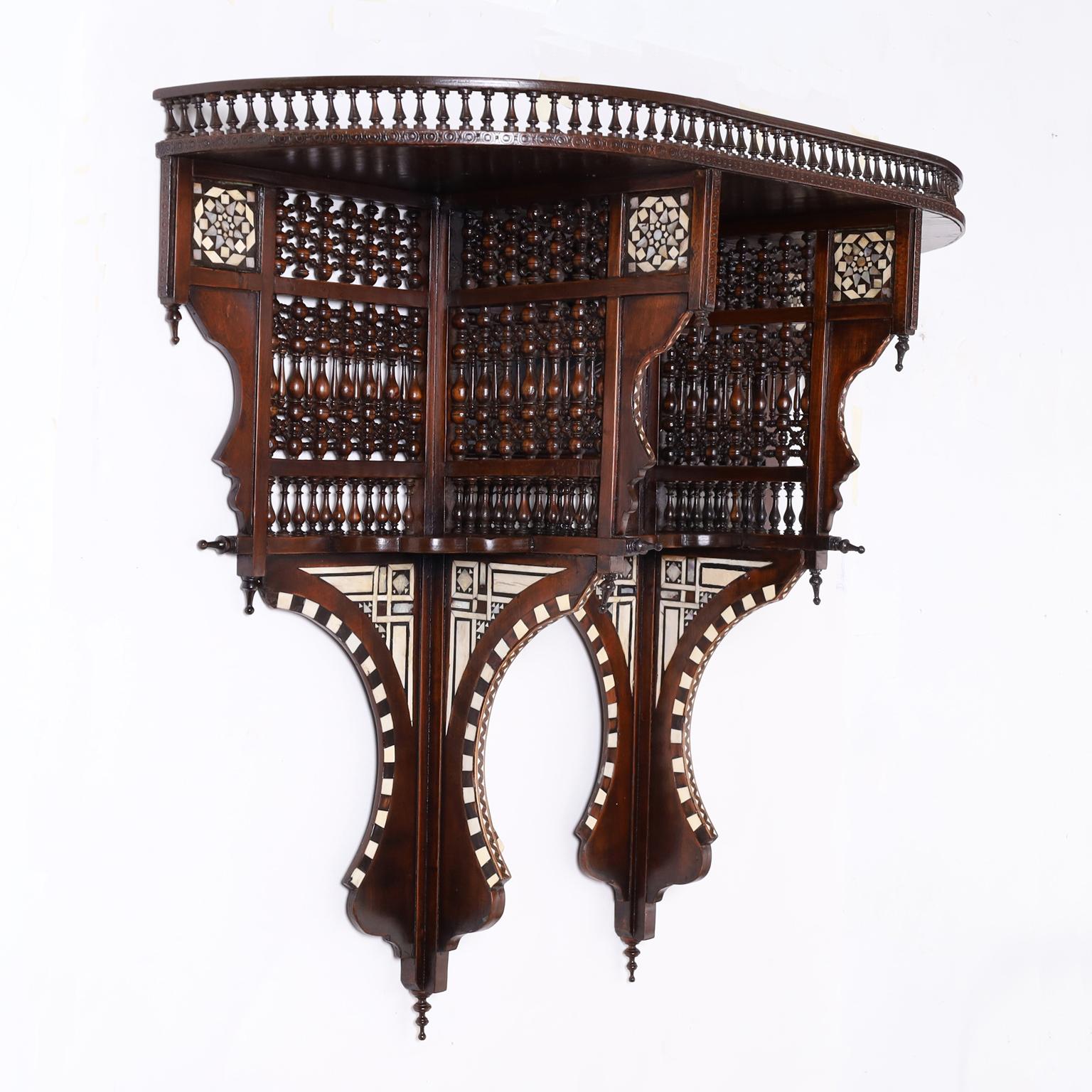Impressive antique near eastern wall shelf crafted in walnut and featuring bone, mother of pearl, and ebony floral and geometric inlays, a gallery, balustrades, stick and ball finials, and moorish arches. 
