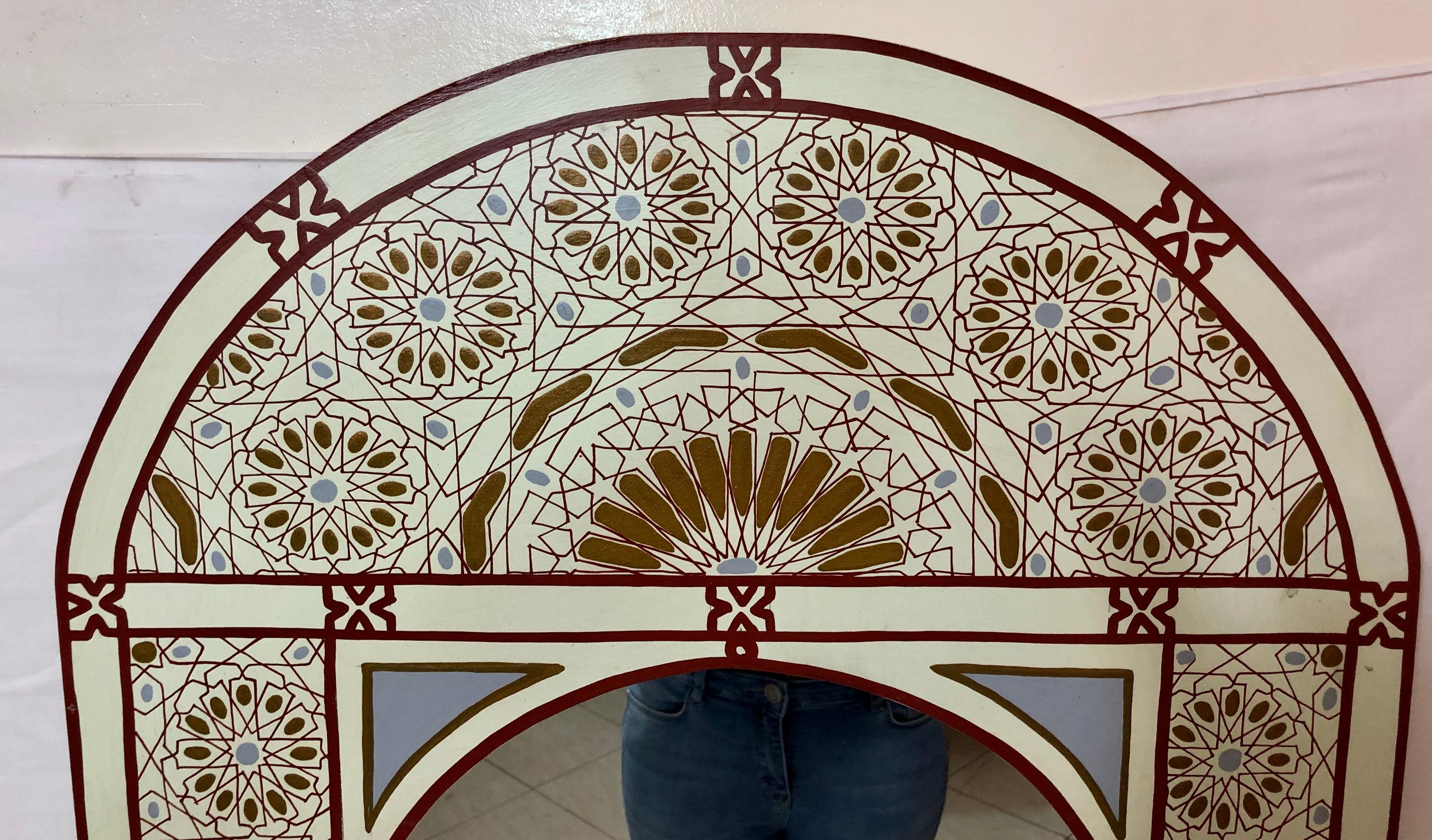 A chic and exquisite vintage hand painted Moroccan wall, console or vanity mirror. The mirror features fine Moorish geometrical design in burgundy, gold and blue gray on white.