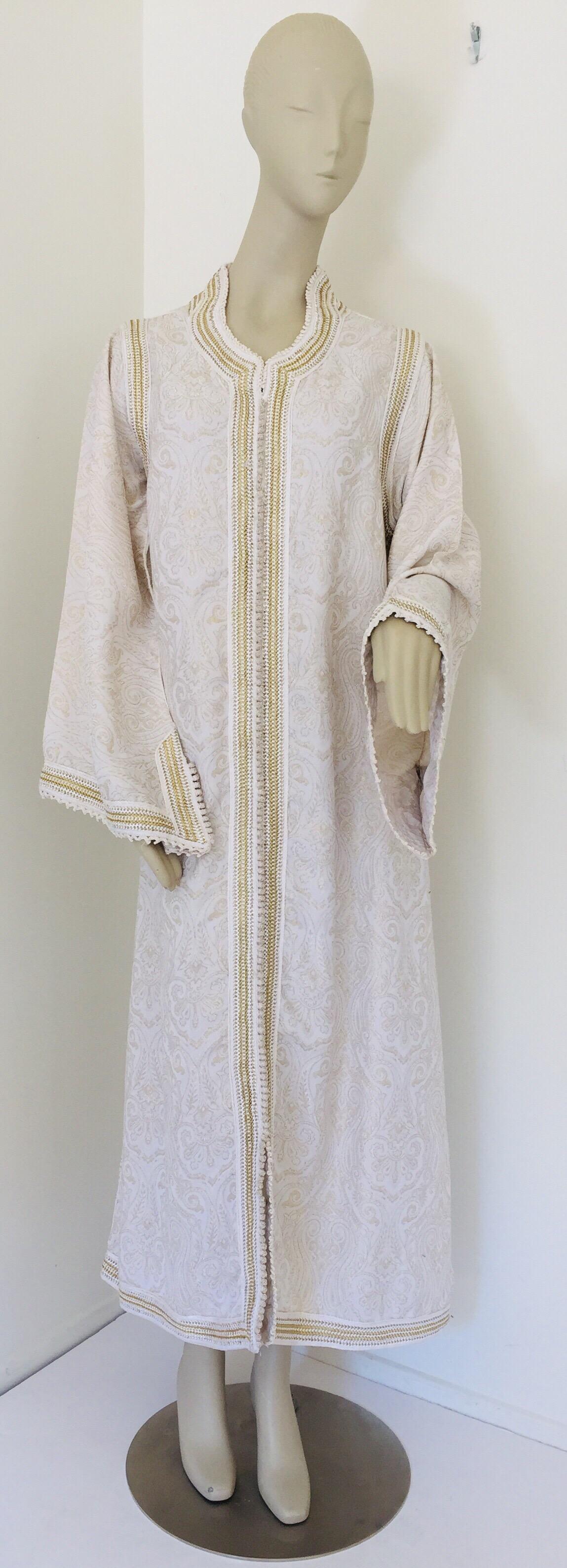 Elegant caftan marocain blanc brodé de fleurs avec des bordures dorées.
La garniture de cette longue robe maxi kaftan est brodée et embellie entièrement à la main.
Robe de soirée marocaine du Moyen-Orient, unique en son genre.
Le kaftan présente une