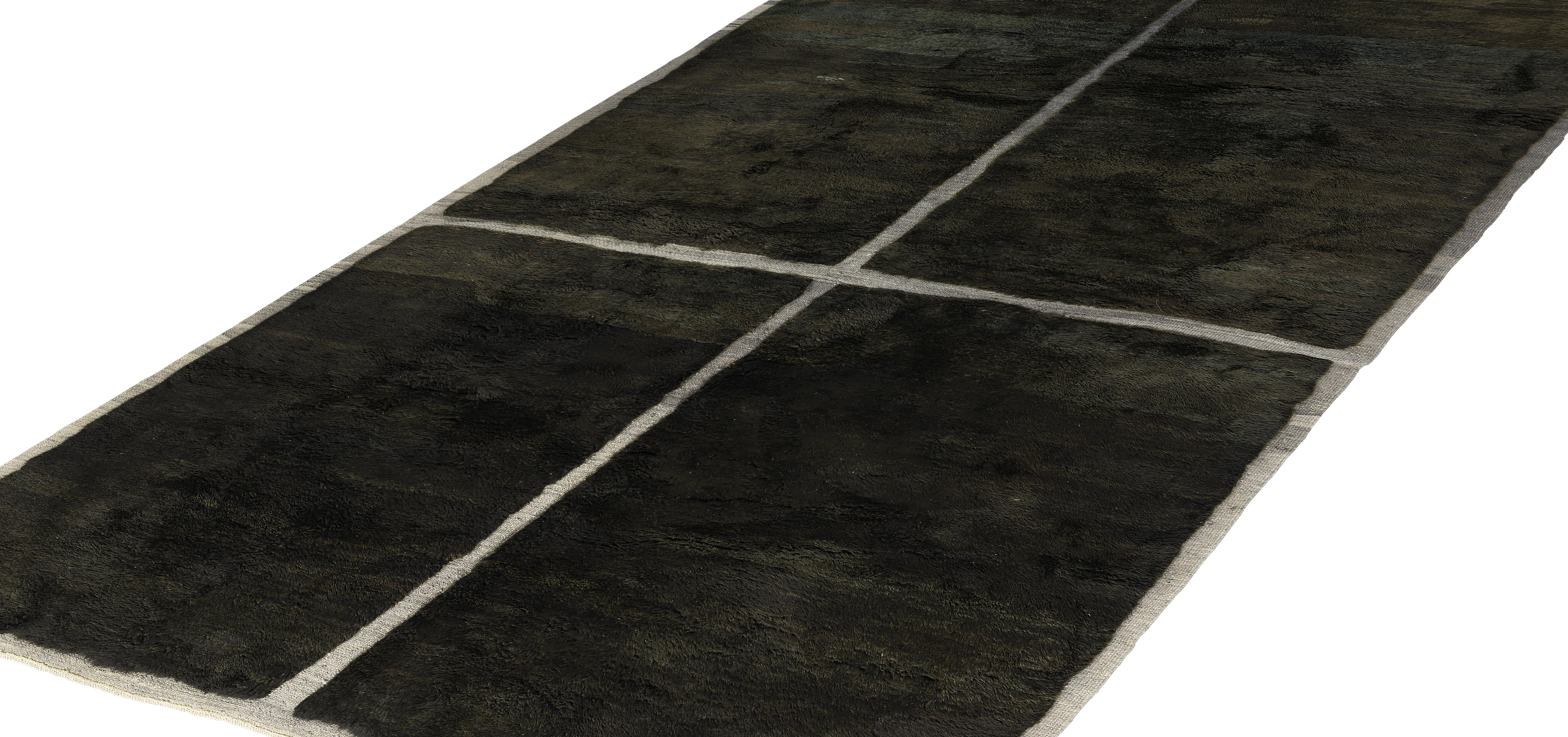 This hand-knotted Moroccan wool rug showcases a bold minimalist design with a soft black field divided into four equal rectangles by a crisp ivory grid. The subtle tonal variations in the wool create texture and depth, adding warmth to the modern,