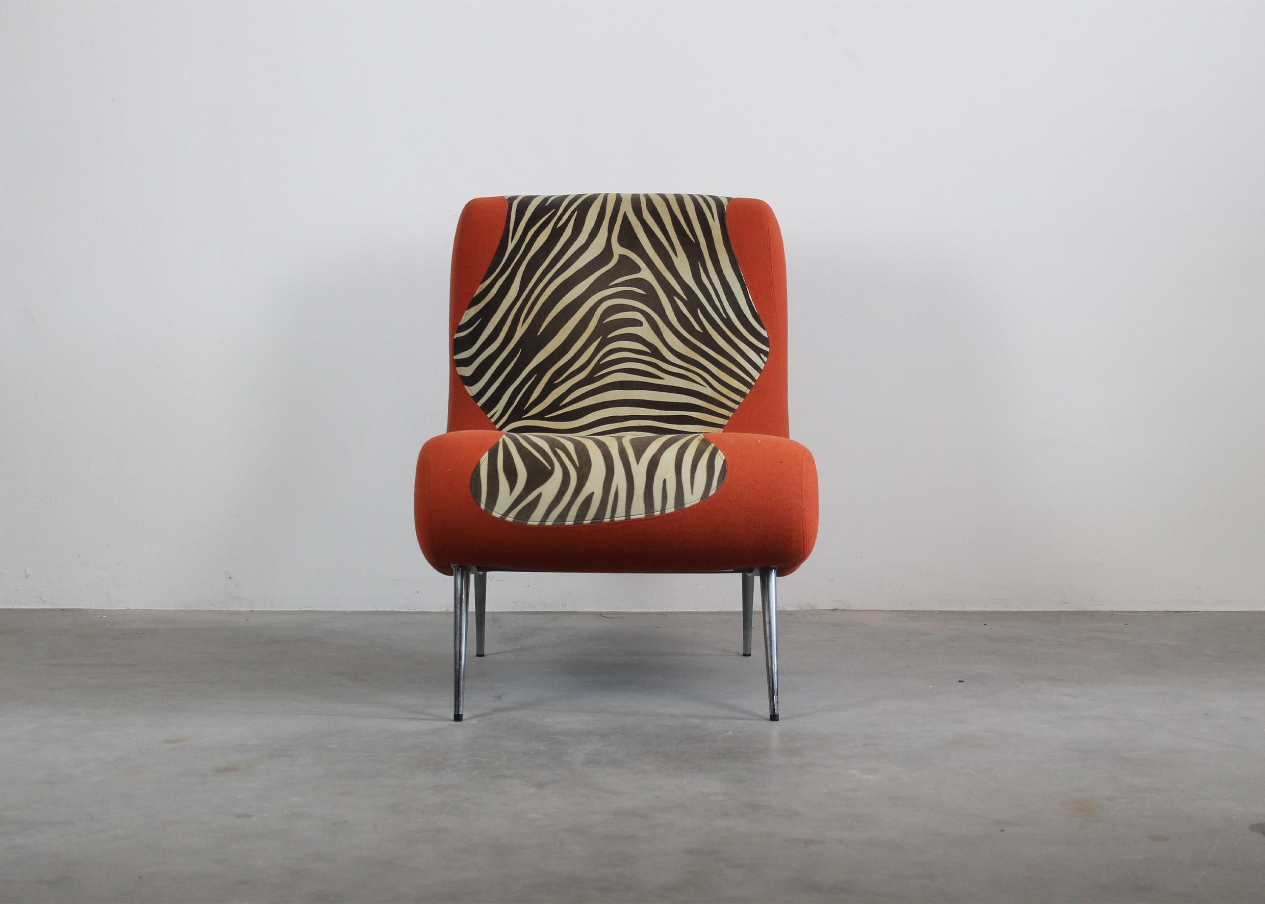 A single armchair without armrests with metal legs, seat, and back realized in padded orange fabric with a central zebra print.

Produced by the Italian company Moroso during the 1990s.

Moroso was established in 1952. It was the brainchild of