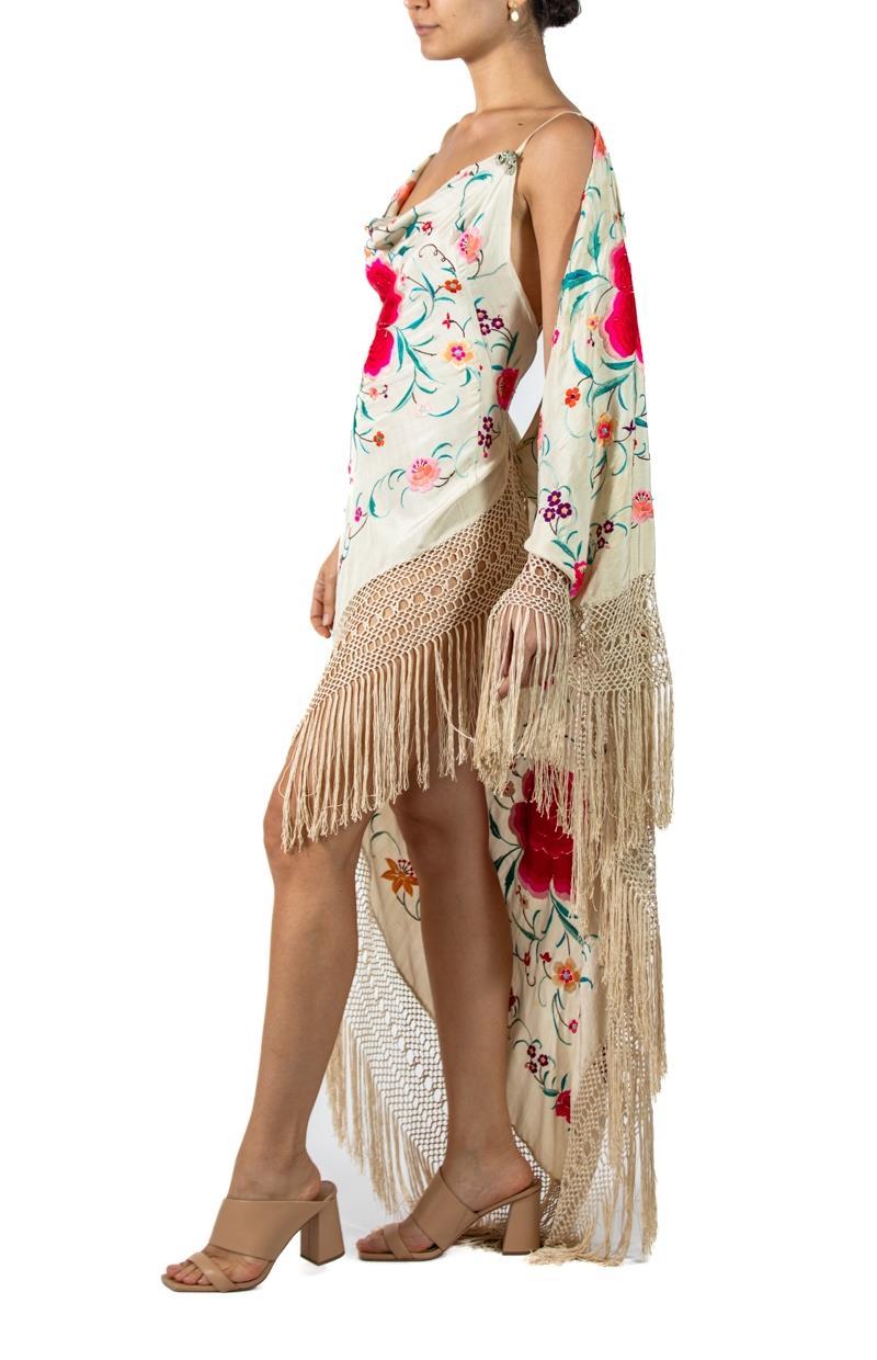 Each Piano Shawl gown is individually draped and thus no two are exactly alike and very minor flaws may exist in the vintage materials. Morphew Atelier Cream Silk Crepe Draped Sleeve Piano Shawl Gown Covered In Floral Embroidery With Fringe 