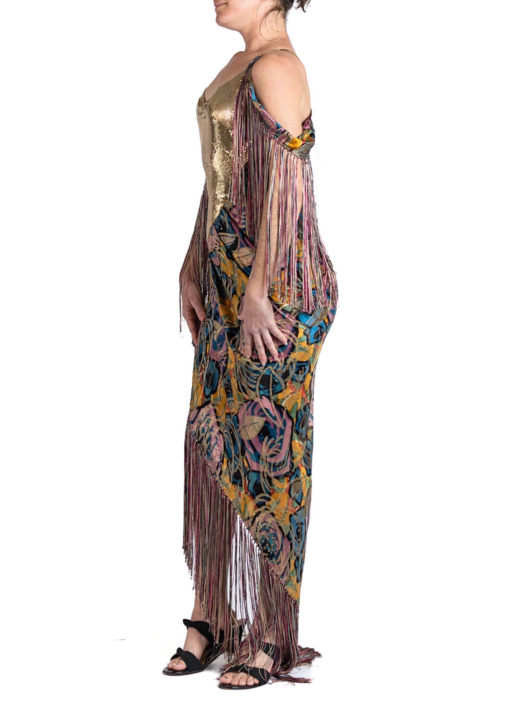 Made from antique 1920s art Deco silk lamé, this gown is draped on the bias and thus will fit a size 0 to a 6. The bodice of the dress is made with vintage gold plated metal mesh which slinks down and frames the opening of the slit. Two removable