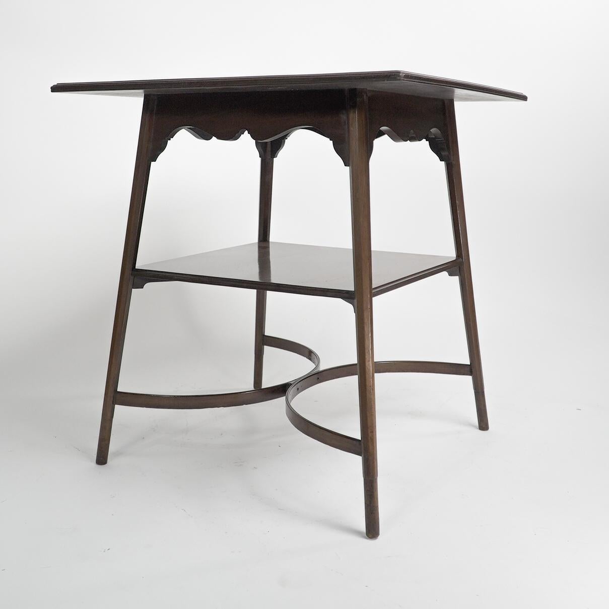 Morris and Co. Designed by George Jack. 
A superior quality Aesthetic Movement two tier walnut side table, with a shaped apron below the top and fine double crinoline stretchers, stood on octagonal legs with tuned feet.