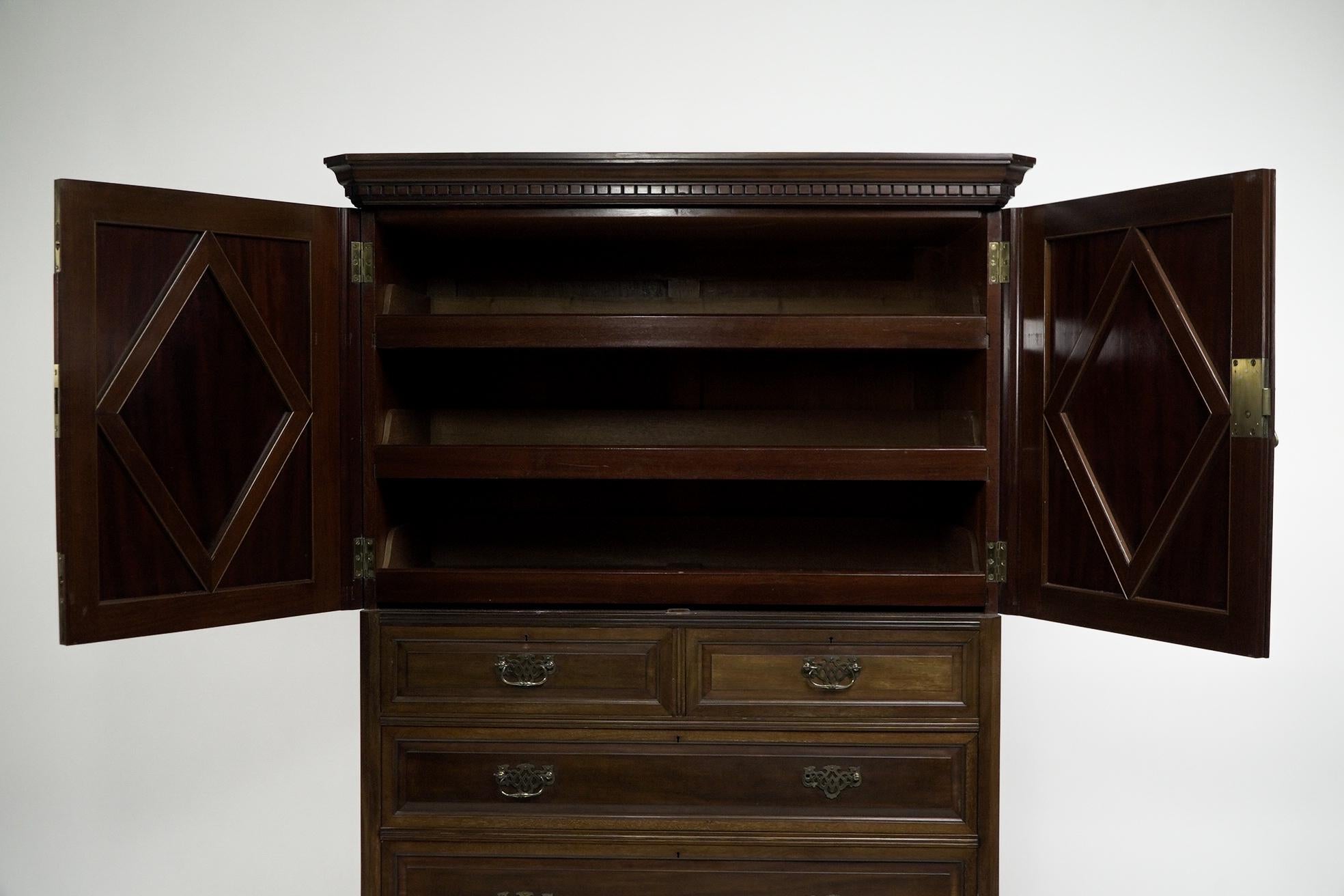Morris and Co. A Superior Quality Aesthetic Movement Walnut tallboy, with a polished top and dentil molding below with fielded diamond shaped panels to the upper doors opening to reveal three open sliding drawers, with two over tree graduating