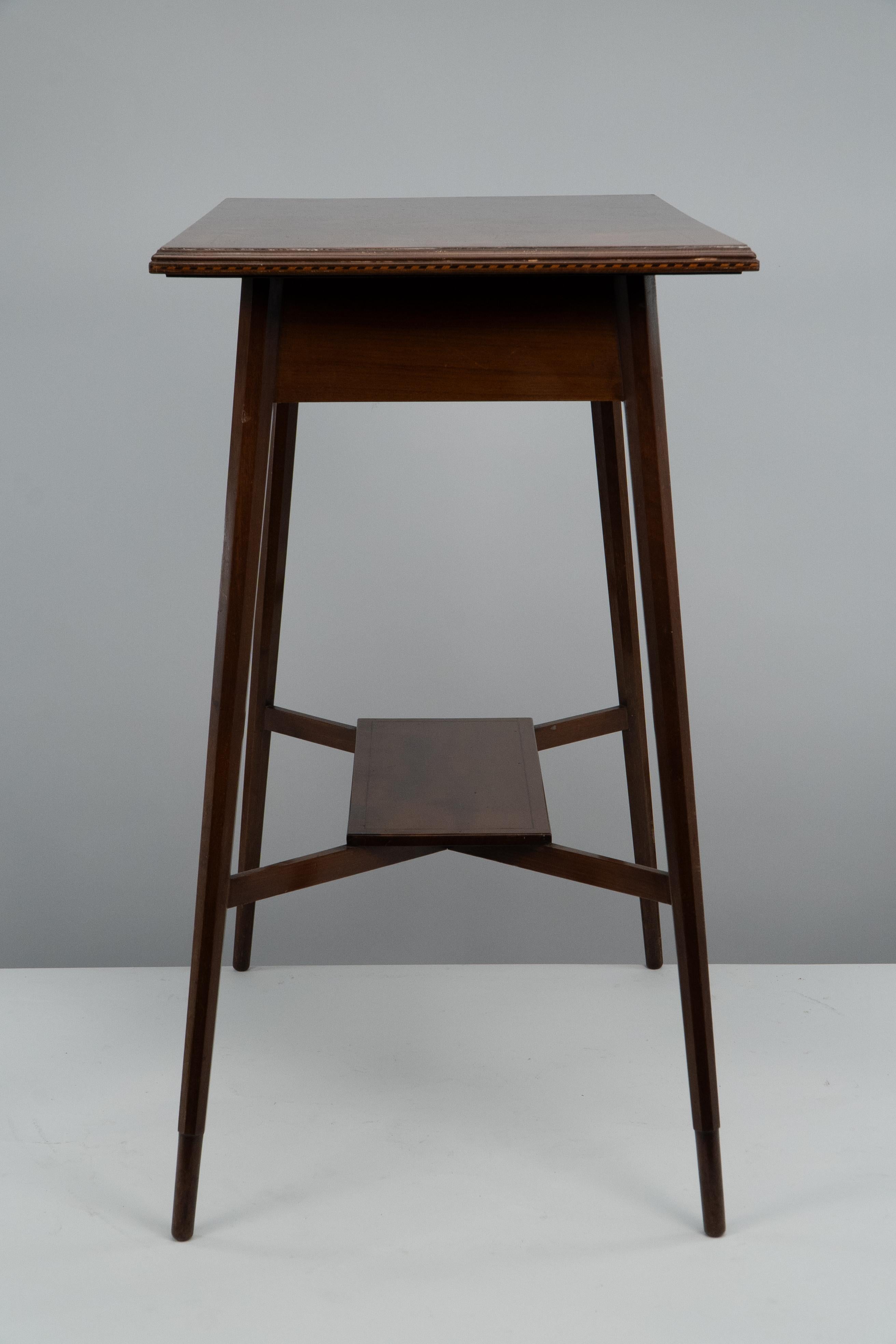 Morris & Co. A fine quality Aesthetic Movement walnut side table with herringbone inlay to the top edge, stood on hexagonal shaped legs with a lower shelf