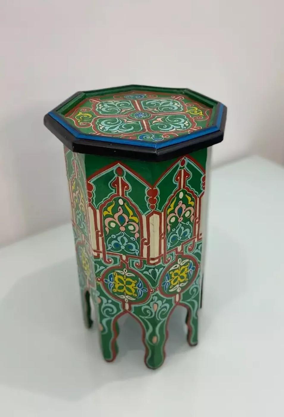 Ein handbemalter Beistelltisch der europäischen Volkskunst im Vintage-Stil mit sechseckiger Platte und geschnitzten, ausgeschnittenen Beinen.

Handbemalt in einer schönen grünen Farbe mit roten, gelben und blauen Motiven.

Dieses Stück eignet sich