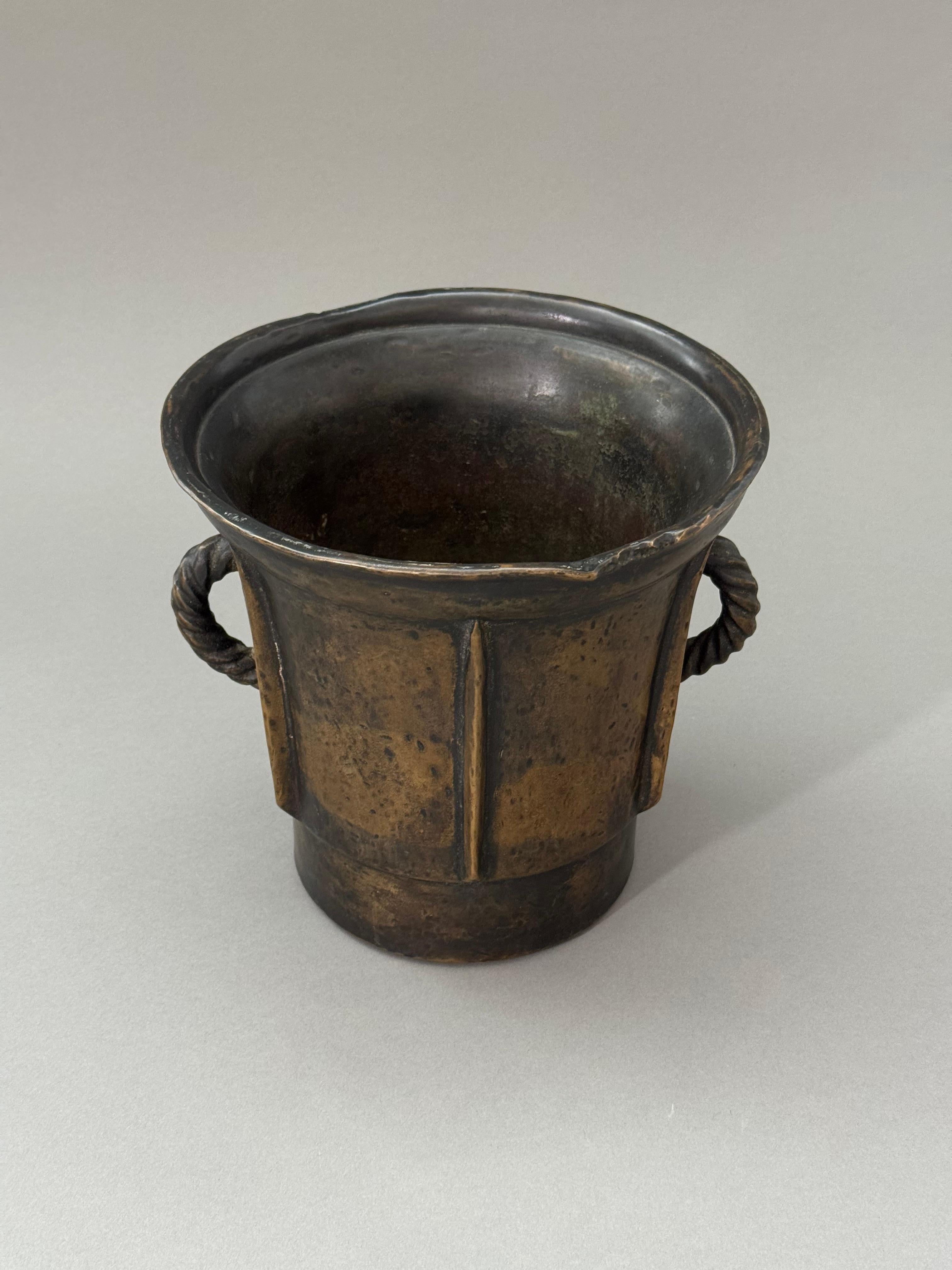 Mortaio in bronzo del XVI secolo toscano. Presenta manici in bronzo a forma di corda e un corpo delineato da linee parallele in rilievo. Storicamente era impiegato in farmacia per la preparazione di composti e miscele. 

Misure: altezza 20 cm