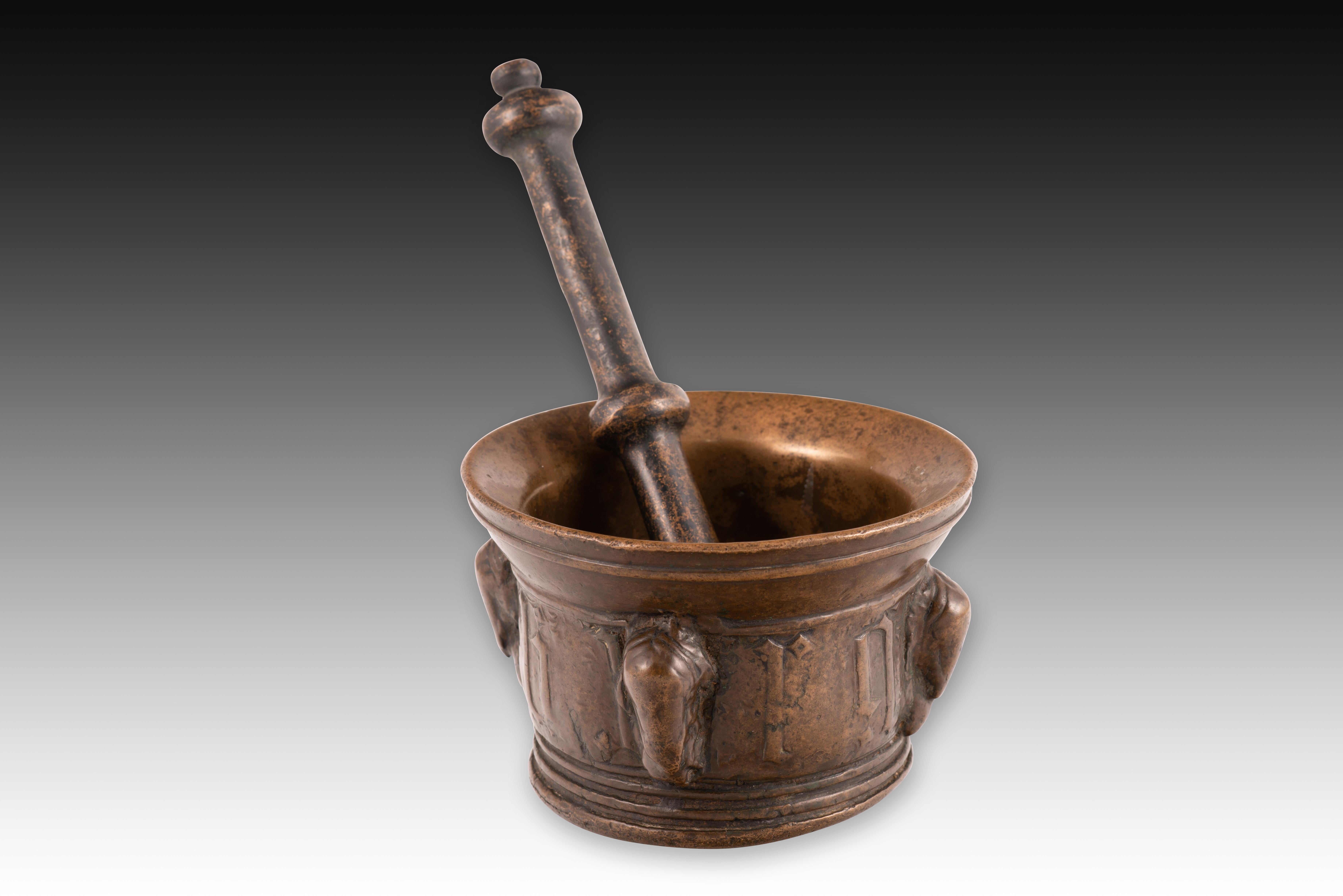  Mortier et pilon. Bronze. 15e siècle. 
Mortier et pilon en bronze avec une base circulaire et un bec verseur décoré d'une bande sous le bord. La base, tournée vers l'extérieur, présente trois lignes lisses en relief, au-dessus desquelles apparaît