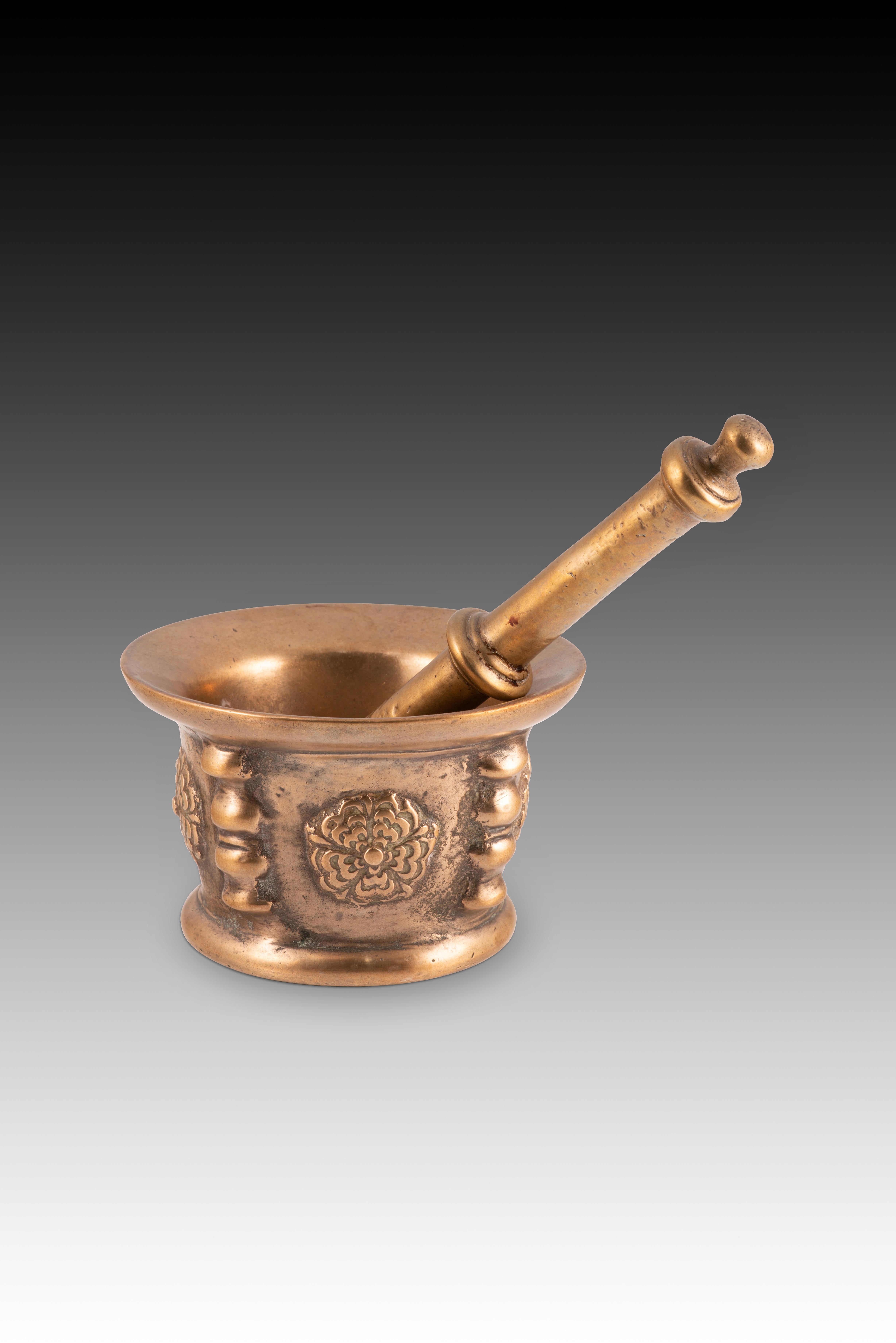  Mortier et pilon. Bronze. XIXème siècle. 
Mortier à bouche évasée et décoration extérieure en relief à base d'éléments en balustrade (rappelant les nervures que ces objets avaient souvent dans l'école espagnole à l'époque gothique) alternant avec