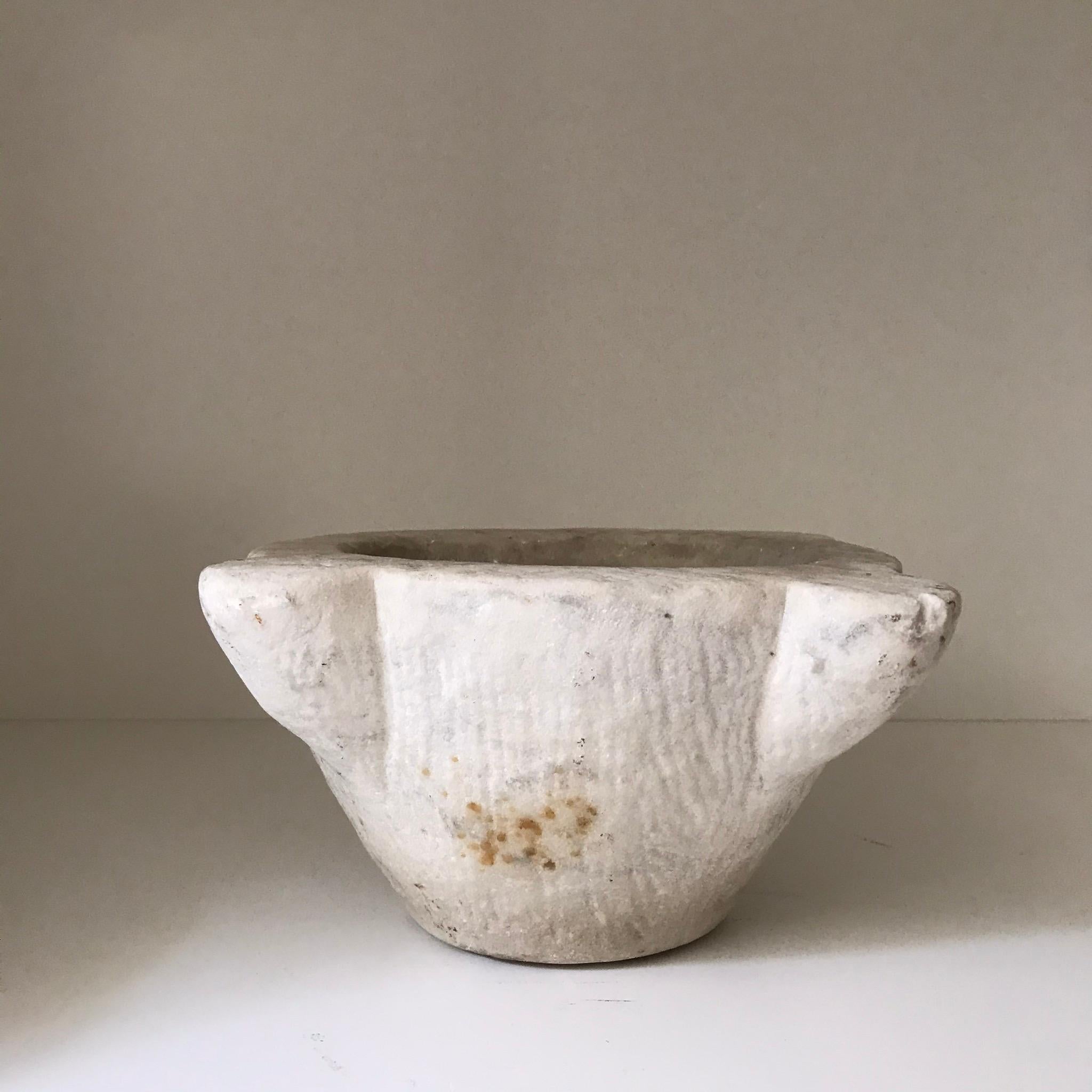 This 19th century marble mortar has a uniquely rough, hand hewn finish from its hand carved construction and age. Originating in France, the mortar has gained a unique patina over the course of the past 150 years as a functional object. 