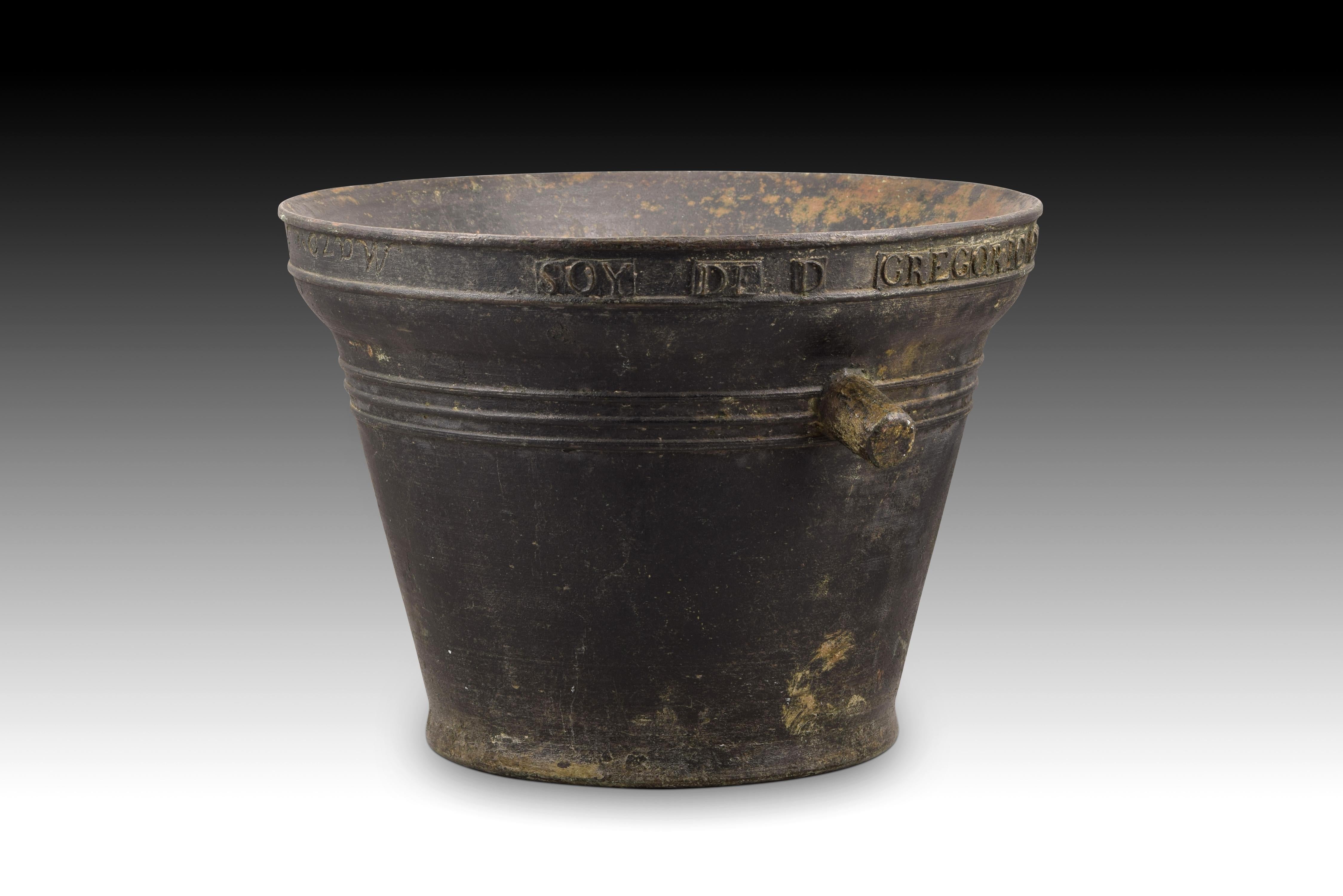 Mortar with inscriptions. Bronze. Spain, 1823. 
Con maza.
Mortar made of bronze with an enlarged mouth and a cone shaped body developed without discontinuity and with a decreasing diameter to the base; It has two handles or 