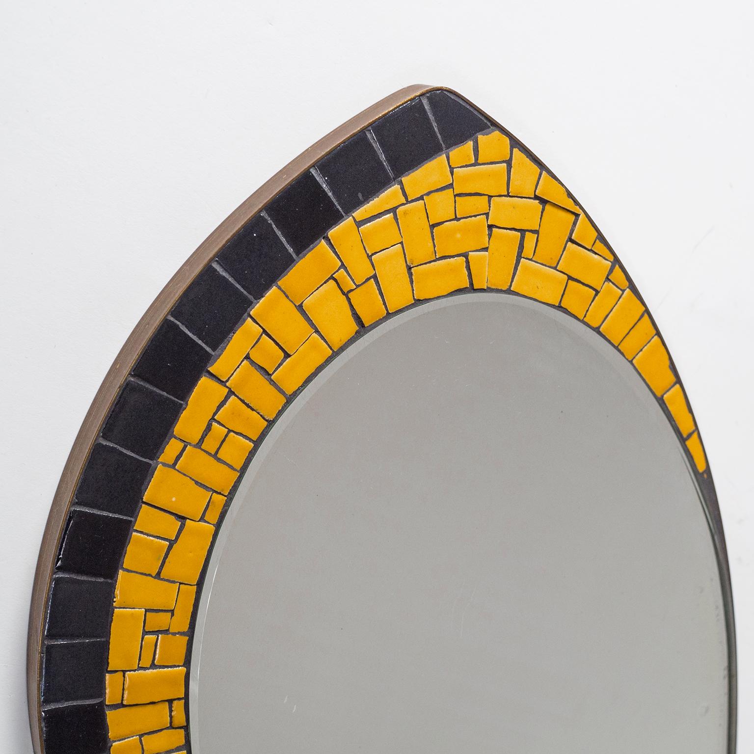 Charming midcentury oval brass and mosaic mirror, circa 1960. Solid continuous brass rim and an asymmetric ceramic mosaic in black and orange. Fine original condition with patina on the brass and some wear to the silver coating of the original