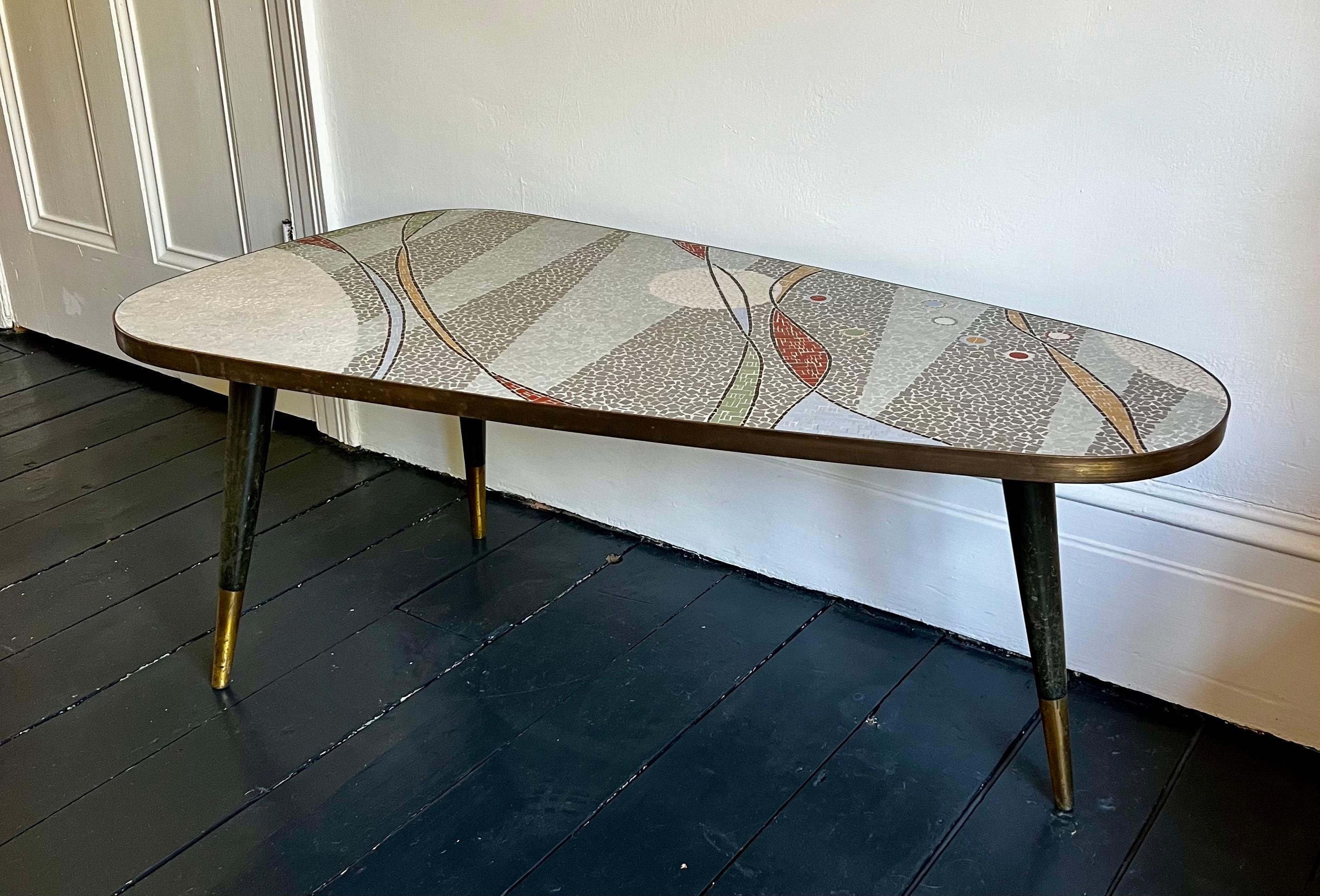 Table basse en mosaïque avec un motif abstrait aux tons pastel et gris. Allemagne, milieu du XXe siècle. Pas de marque de fabrique, mais tout à fait dans le style de Berthold Müller.

La table est formée d'un plateau triangulaire arrondi, décoré de