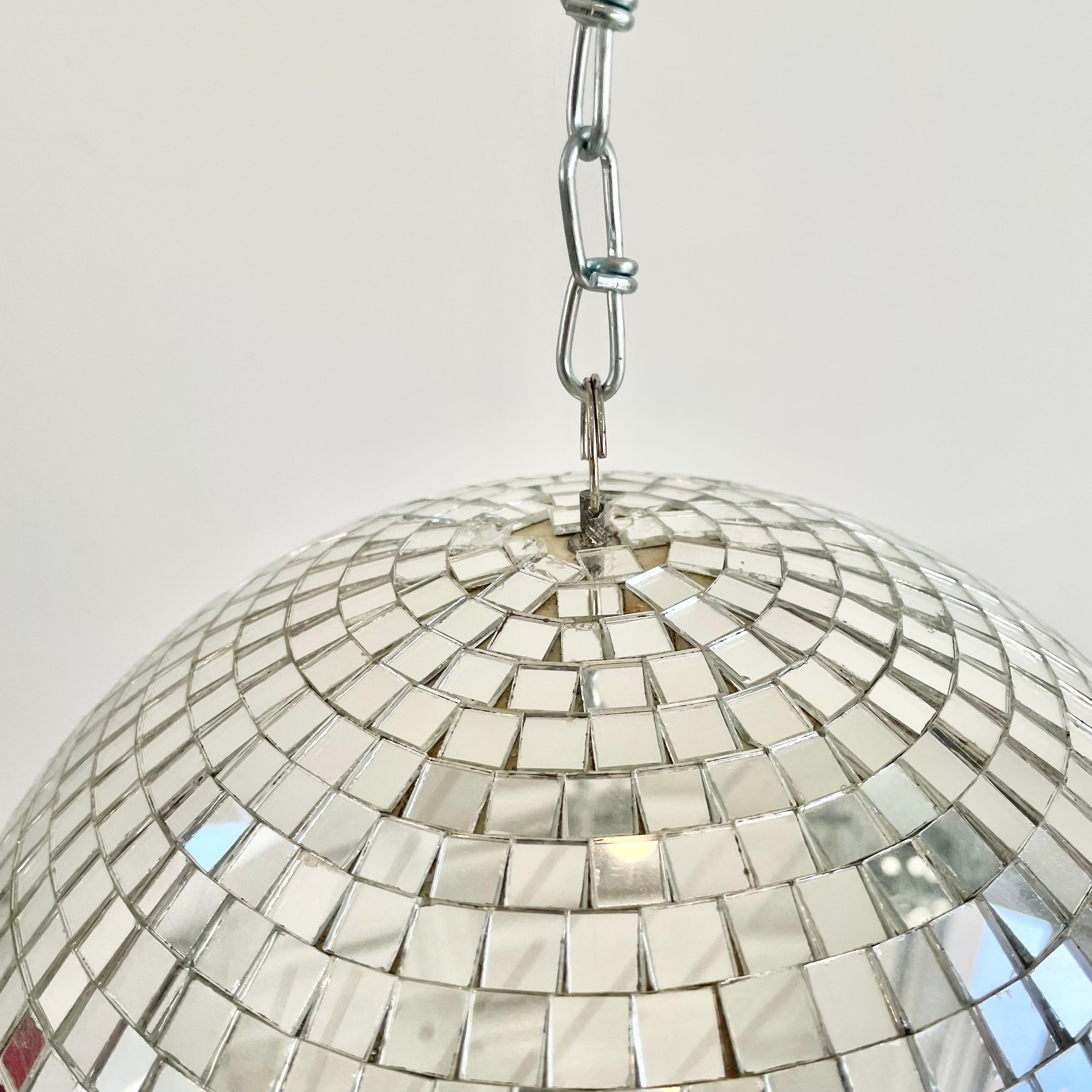 Medium sized retro disco ball made out of small individually cut square pieces of glass giving it a great look. Good condition. Illuminates beautifully. Has a metal ring at the top which is connected to a 3 foot long silver chain link which can be