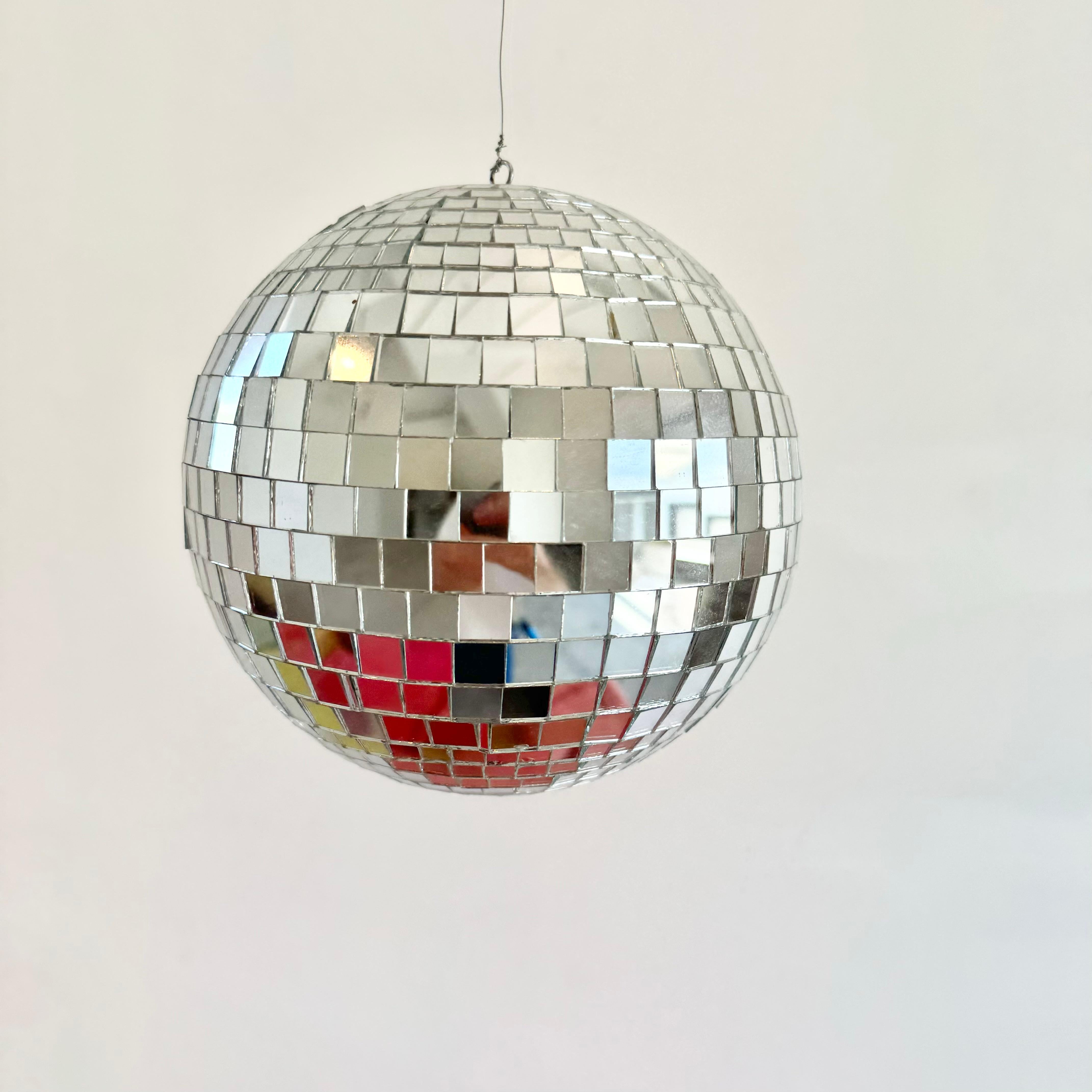 Mittelgroße Retro-Discokugel aus kleinen, einzeln geschliffenen, quadratischen Glasstücken, die ihr ein tolles Aussehen verleihen. Guter Zustand. Leuchtet wunderschön. Hat einen Metallring an der Spitze, der mit einem 3 Fuß langen Metalldraht
