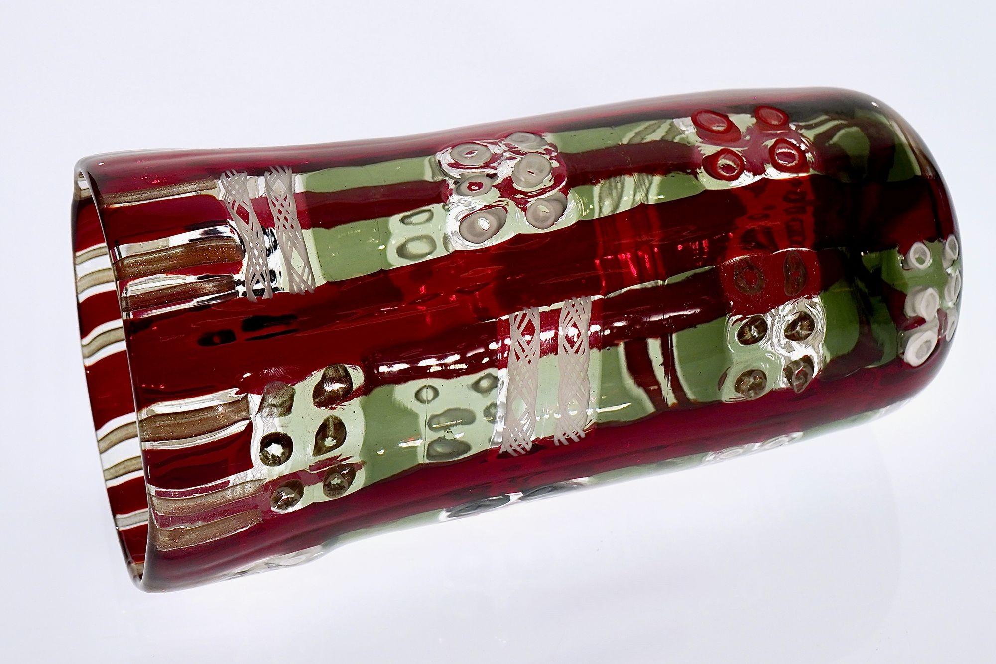 Murano Vase - Mondrian Komposition
Eine unverwechselbare Vase aus Murano mit einer Komposition aus weißen und schwarzen Occhi Murrine, Zanfirico-Rohr und Avventurina-Filigran. Die Anordnung erinnert an eine Mondrian-ähnliche Struktur, in der Rot,