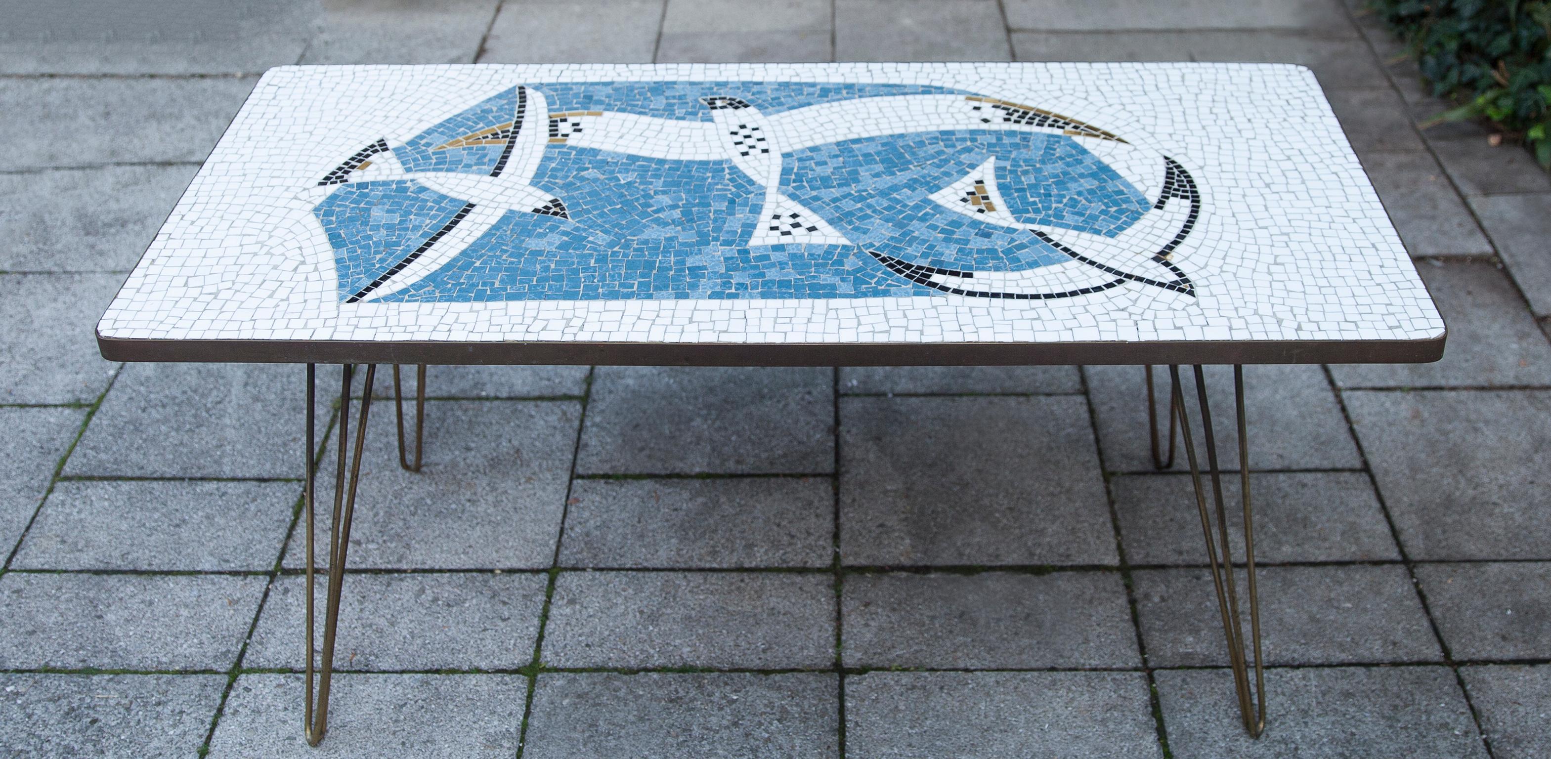 Mosaic coffee table by the German sculptor Berthold Muller, Oerlinghausen (1893-1979). The table have beautiful mosaic pattern of glass mosaic tiles and a brass rim and four brass legs. The colours of the mosaic are blue and white black with three